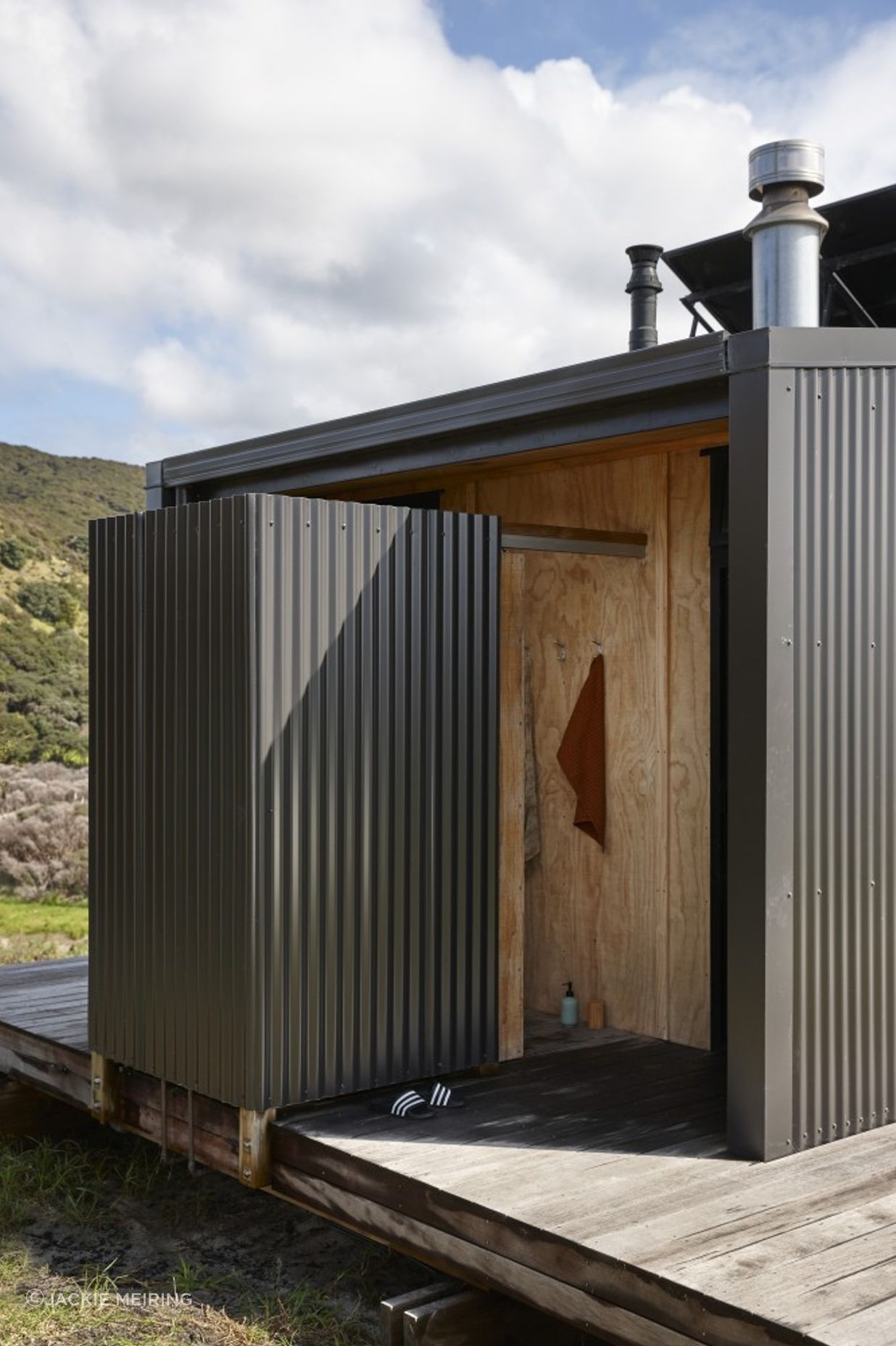 An outdoor shower is formed using corrugated iron and timber.