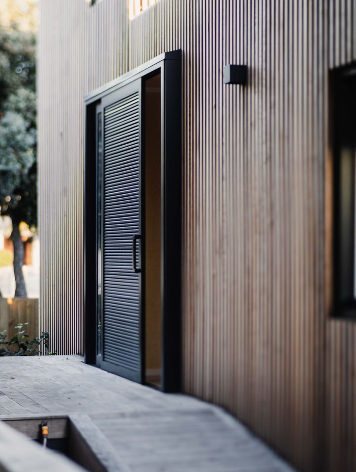 A battened timber screen hugs the painted cladding below.