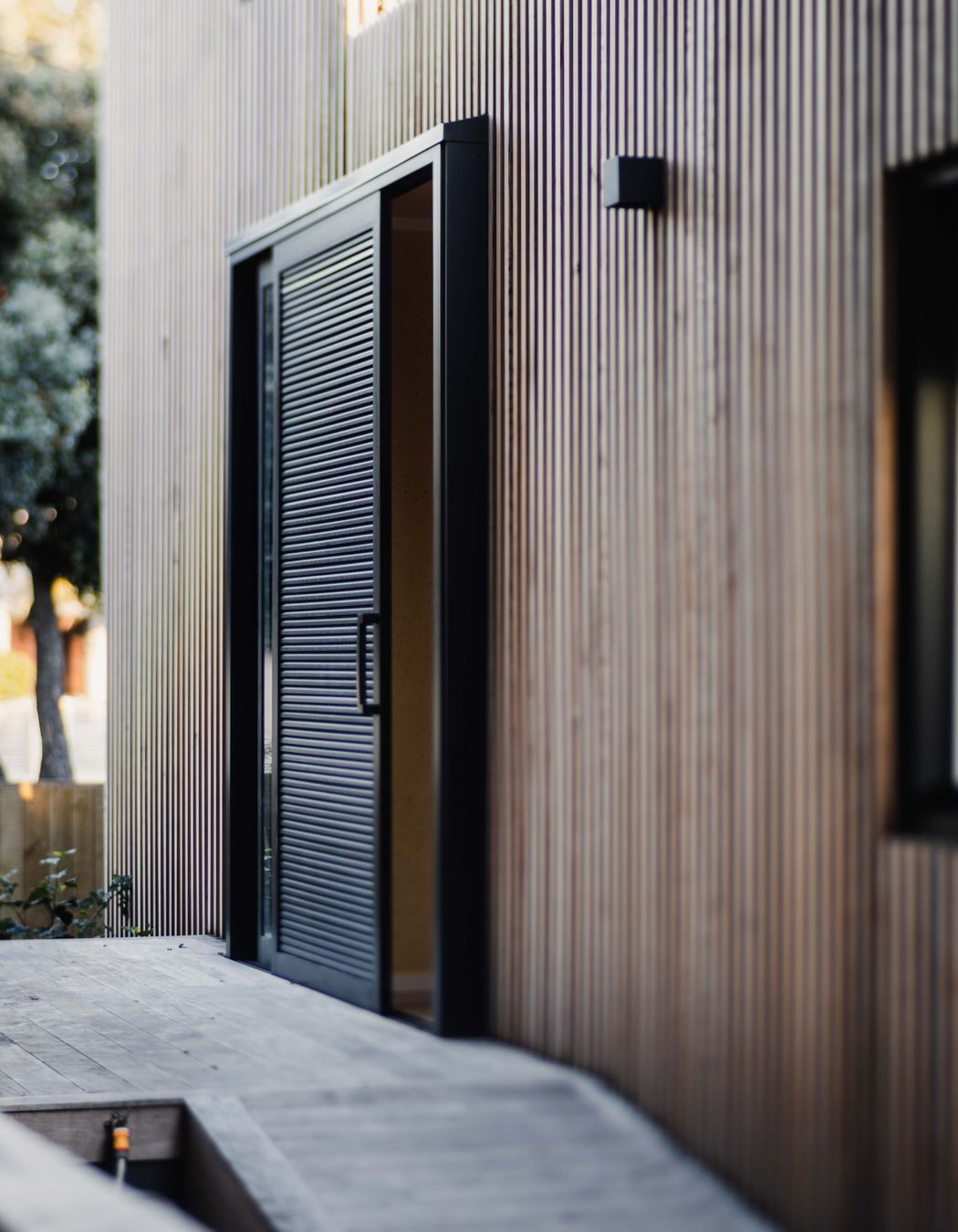 A battened timber screen hugs the painted cladding below.