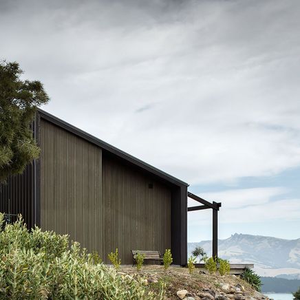 A cave-inspired home rising from a lava flow embankment