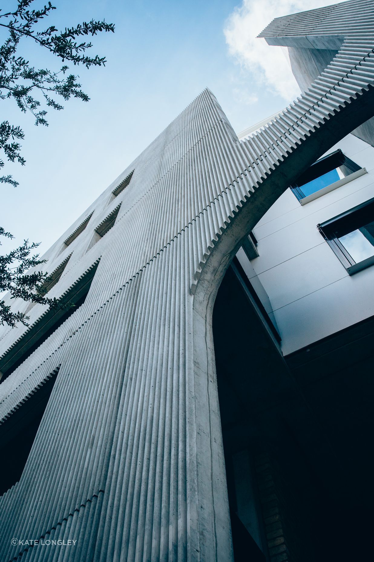 The simple, robust exterior is surrounded by mature trees and greenery.