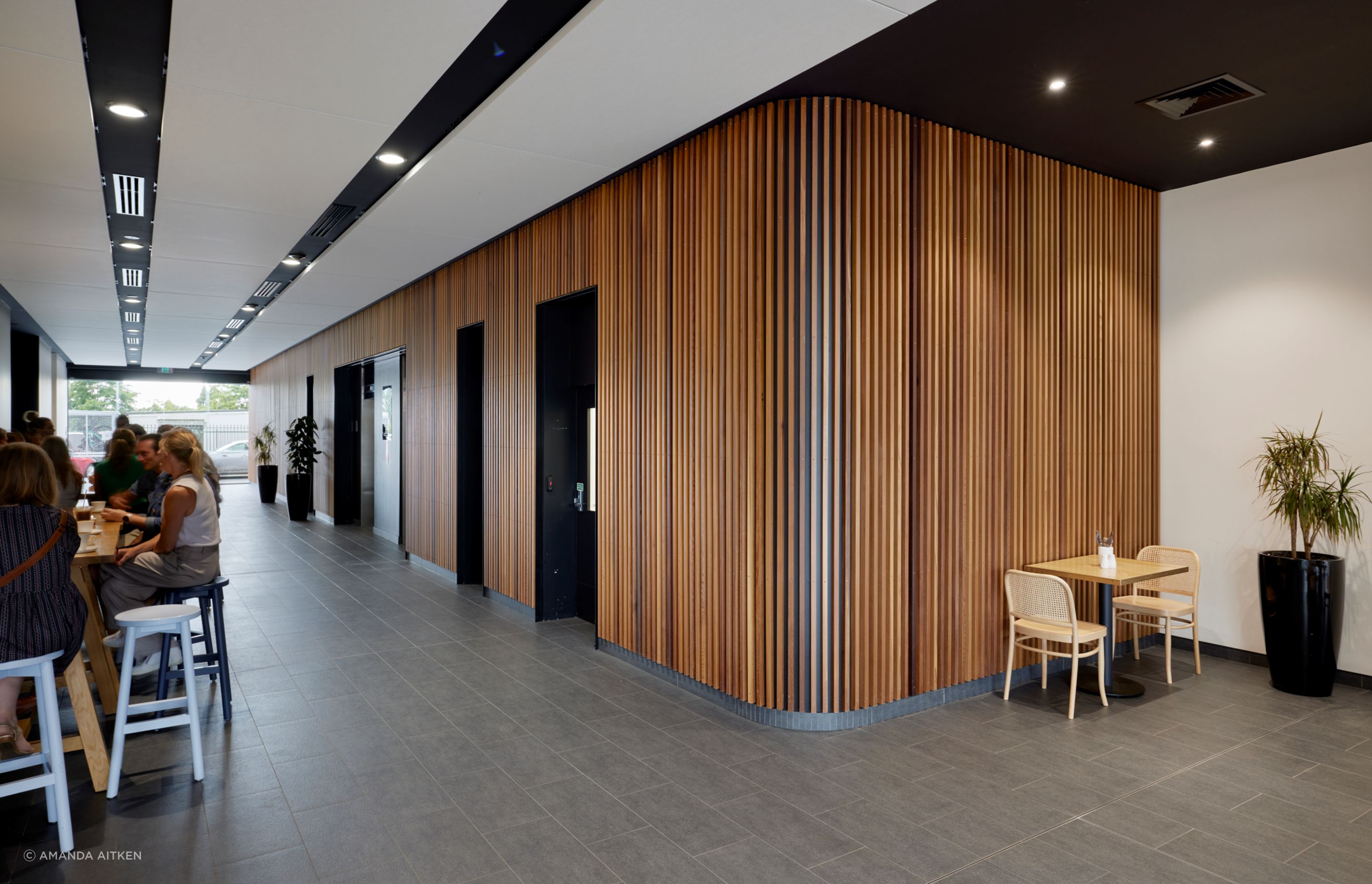 The foyer features a timber slatted wall that wraps right from outside to the lifts.