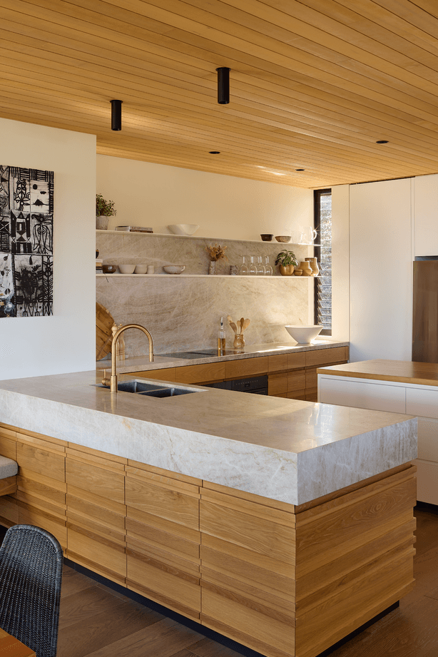 Natural stone complements the timber in the kitchen, which overlooks the dining and lounge areas.