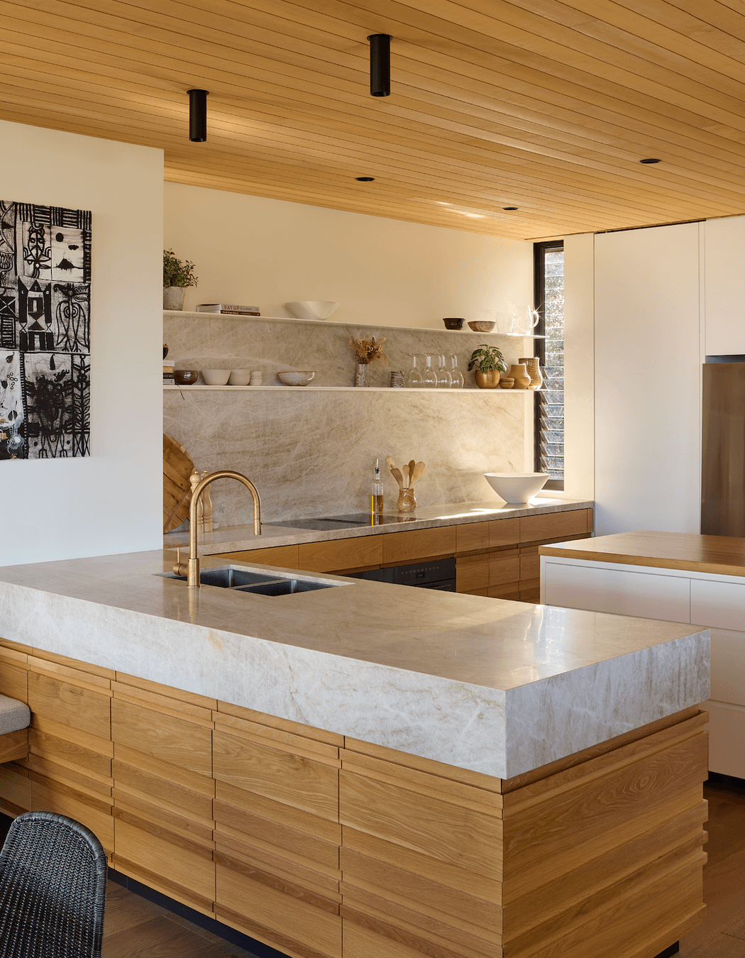 Natural stone complements the timber in the kitchen, which overlooks the dining and lounge areas.