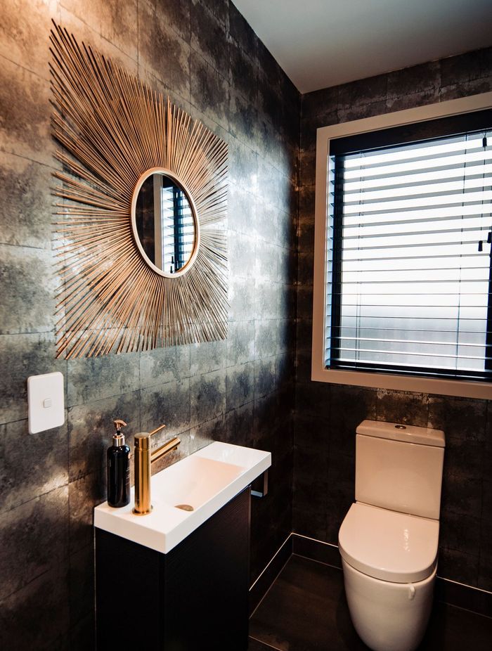 The powder room makes a statement with wallpaper and brass accents.