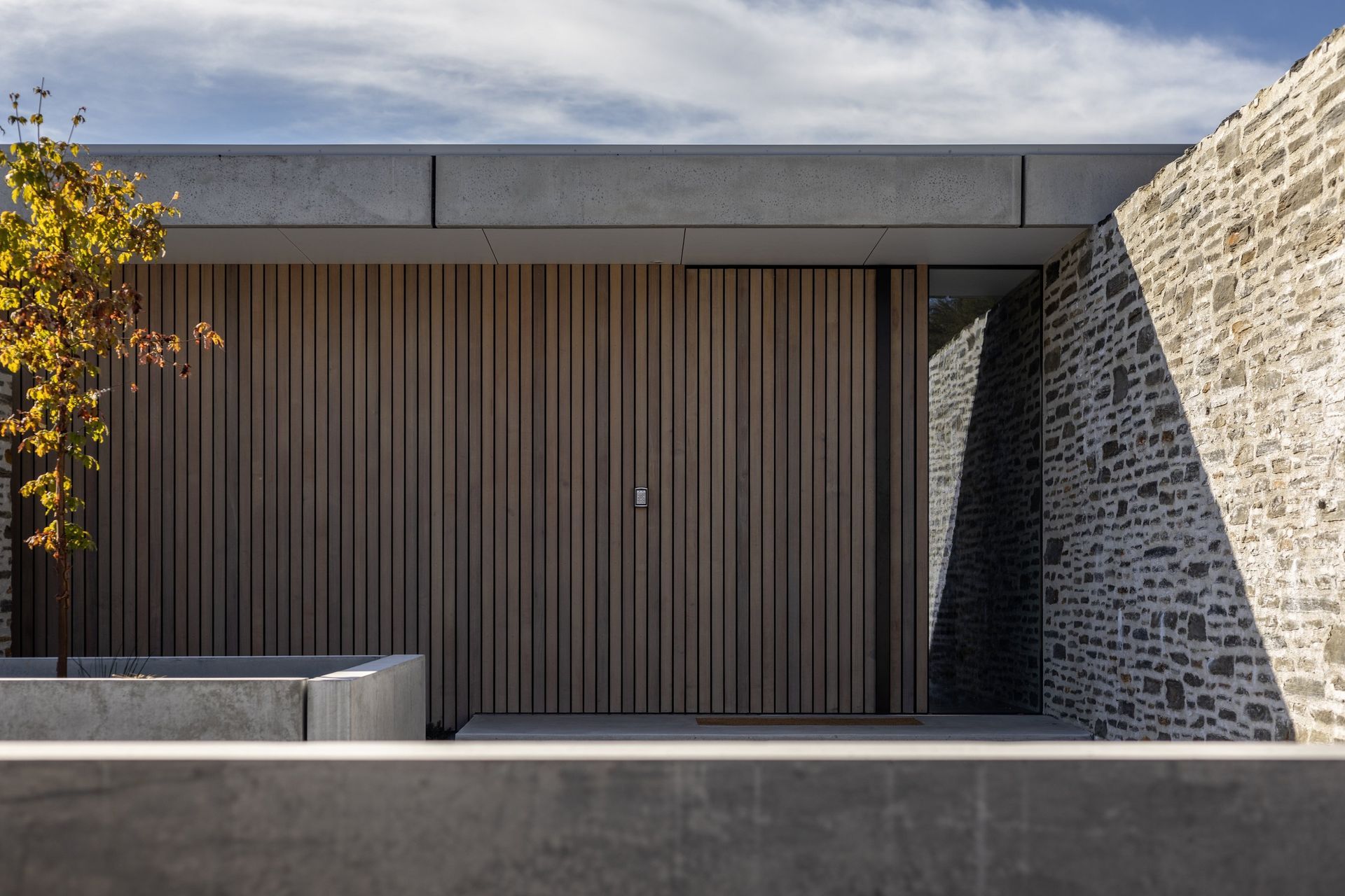 A schist stone wall guides visitors toward the entry.