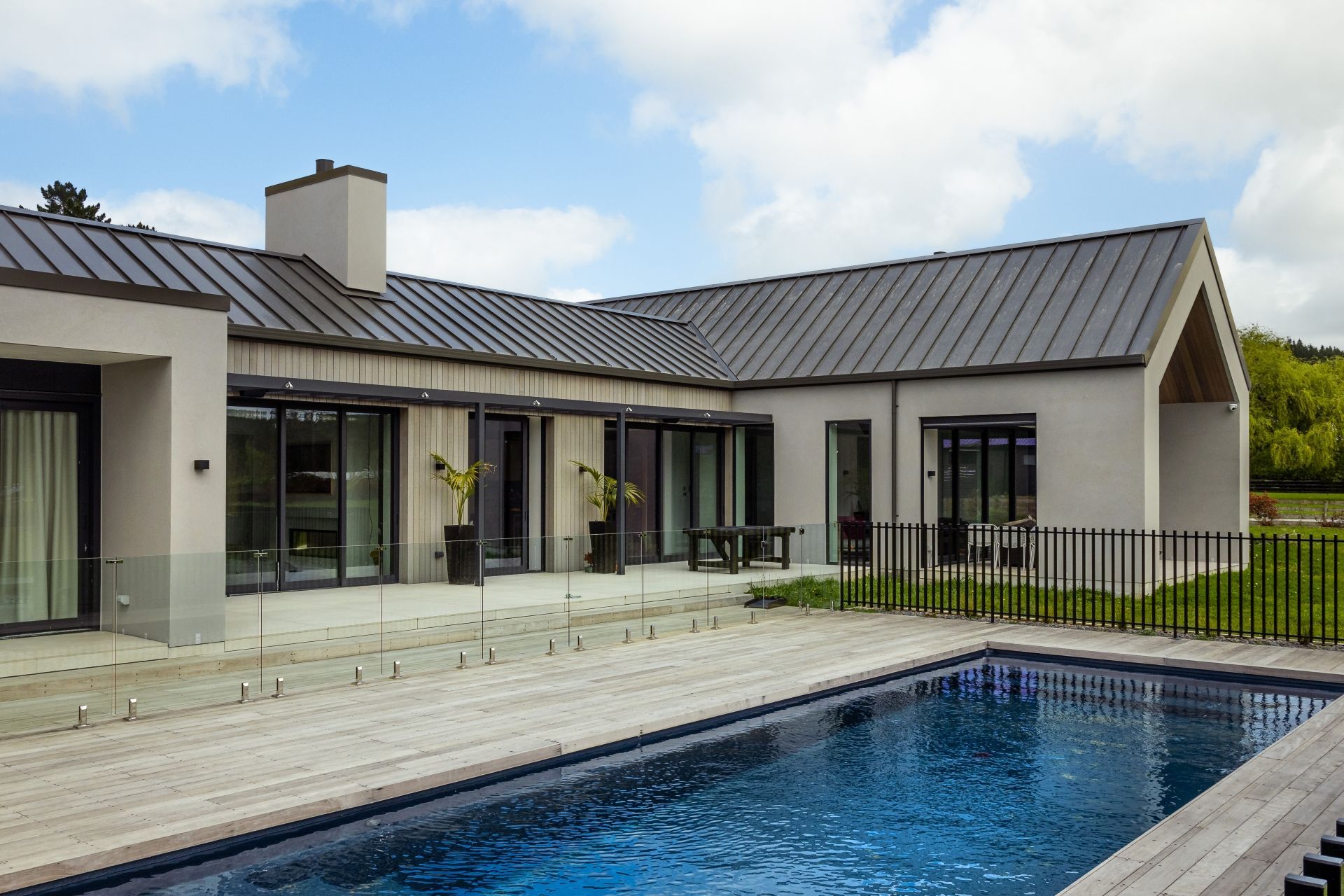 The decking extends out from the back of the home, wrapping around the sides of the pool.