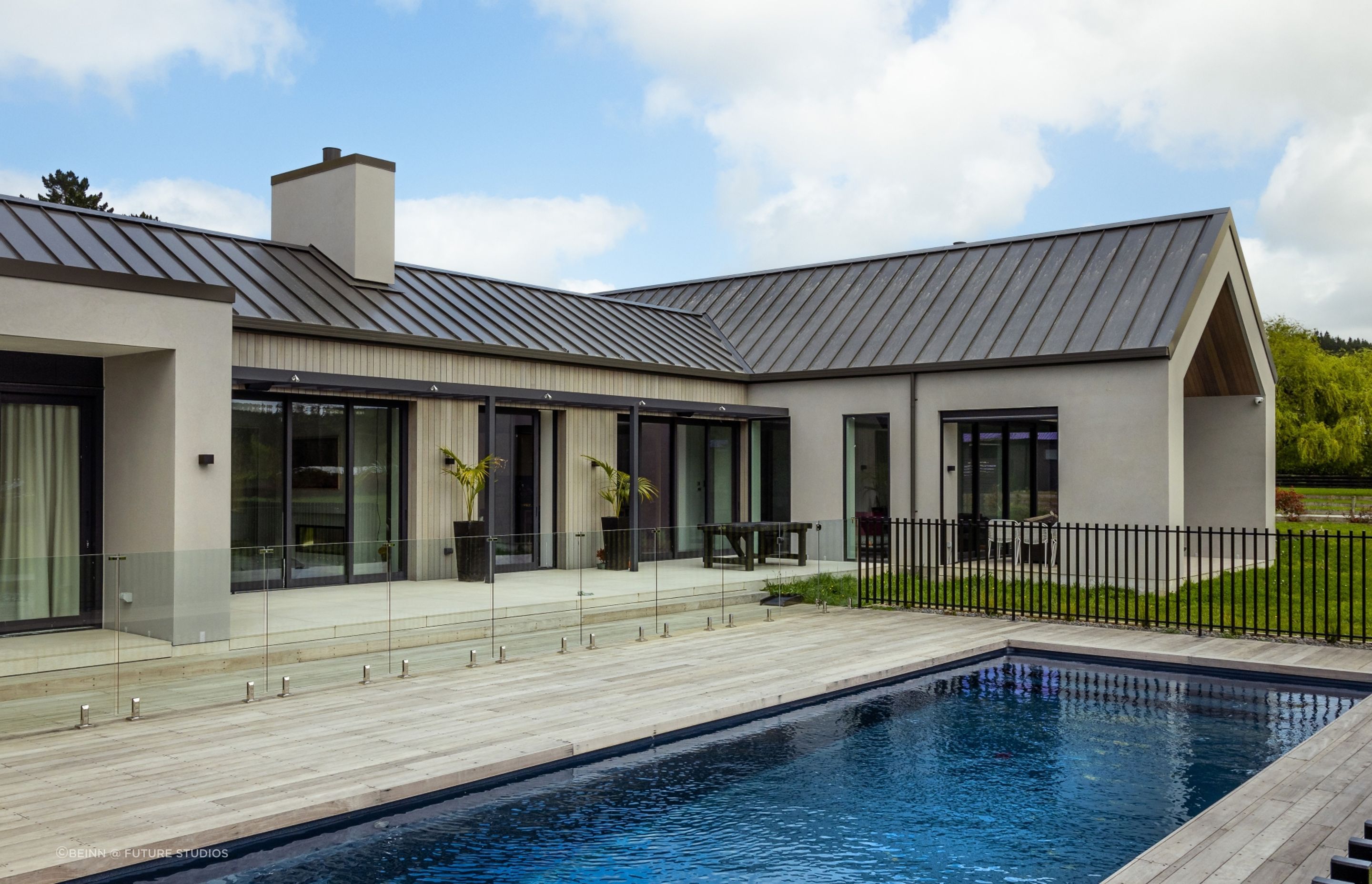 The decking extends out from the back of the home, wrapping around the sides of the pool.