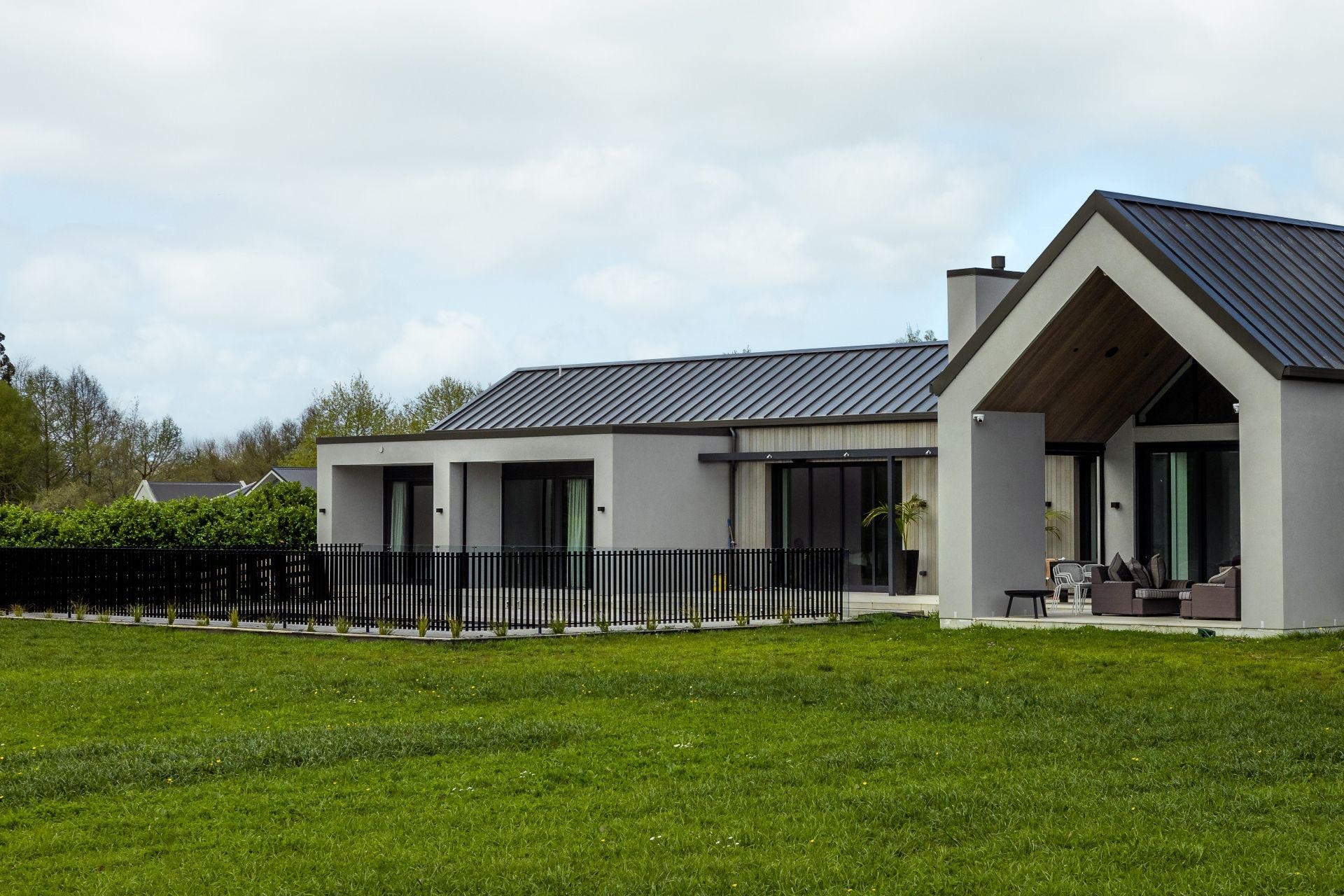 At the rear of the home, a gable form creates an extended eave and outdoor entertaining area next to the fenced pool area.