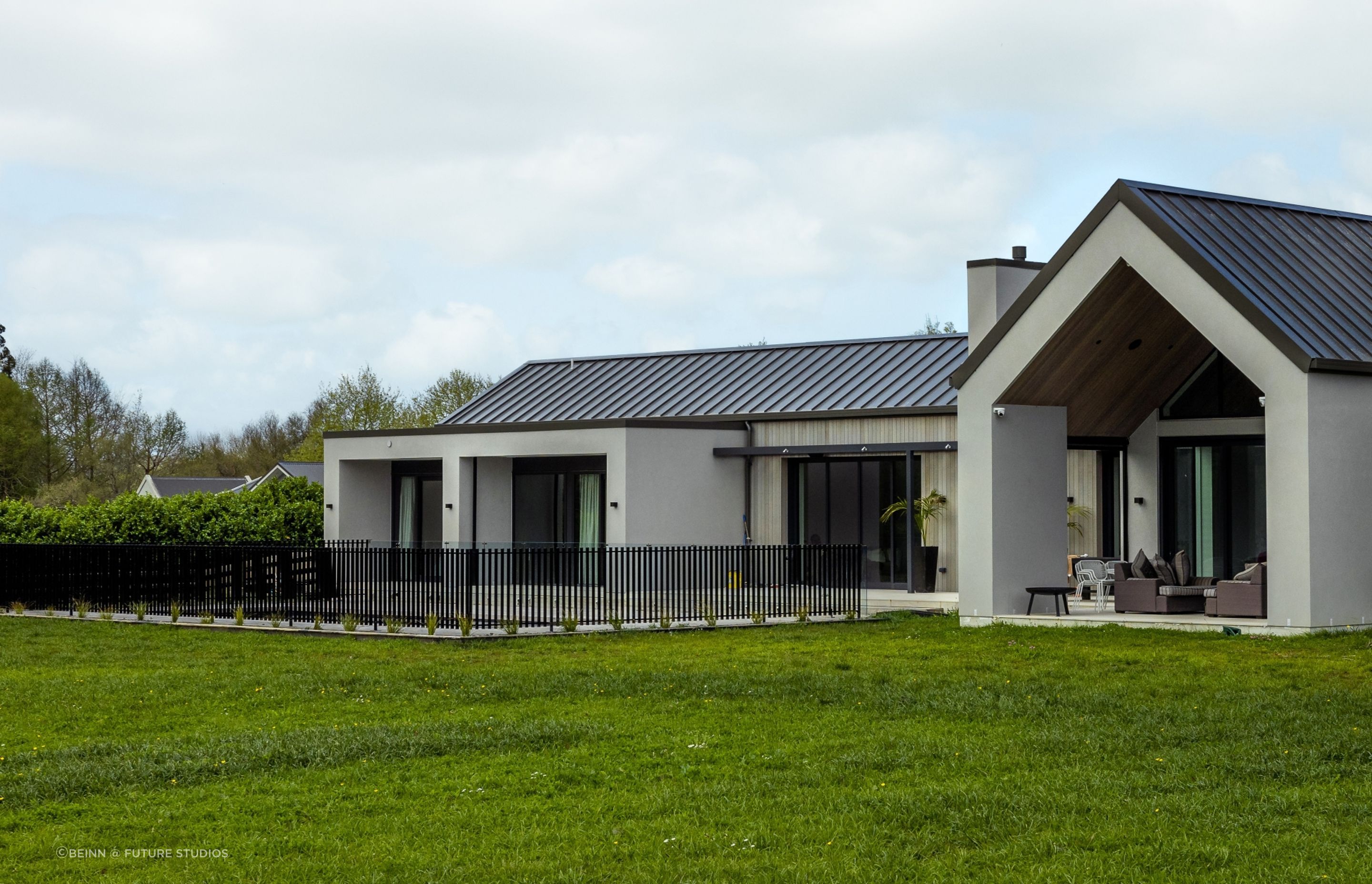 At the rear of the home, a gable form creates an extended eave and outdoor entertaining area next to the fenced pool area.