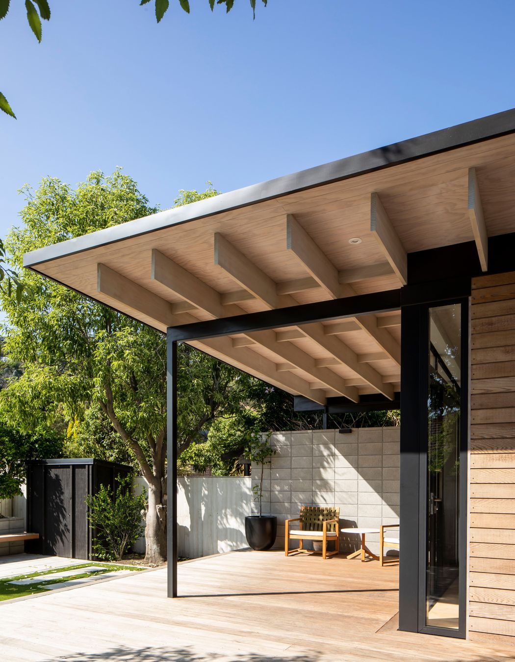 The roof extends past the building envelope to create a sheltered outdoor space, which acts as a second living area and a transition zone between the house and the garden.