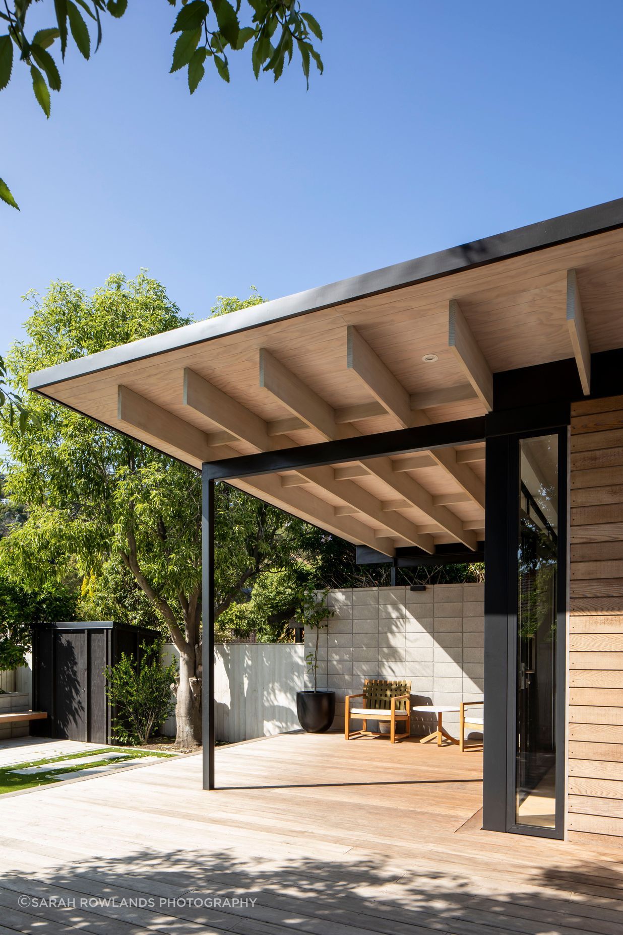 The roof extends past the building envelope to create a sheltered outdoor space, which acts as a second living area and a transition zone between the house and the garden.