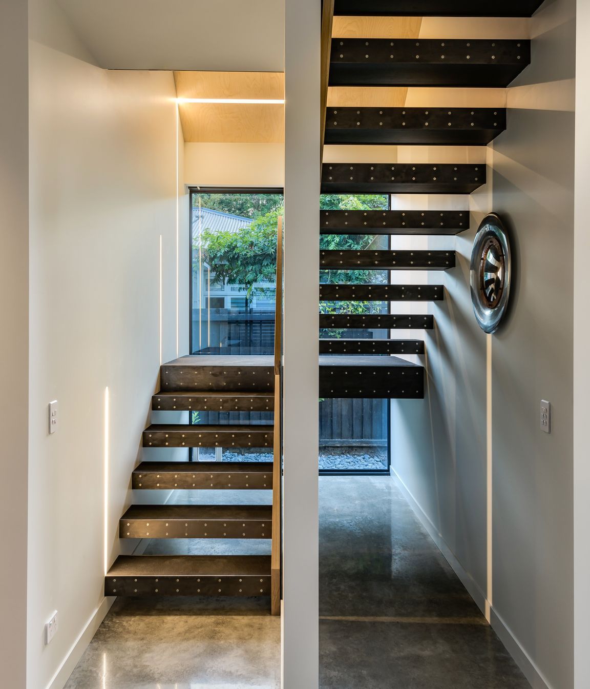 The staircase has an exposed metal stringer, with rubber-clad treads and mild steel fronts.