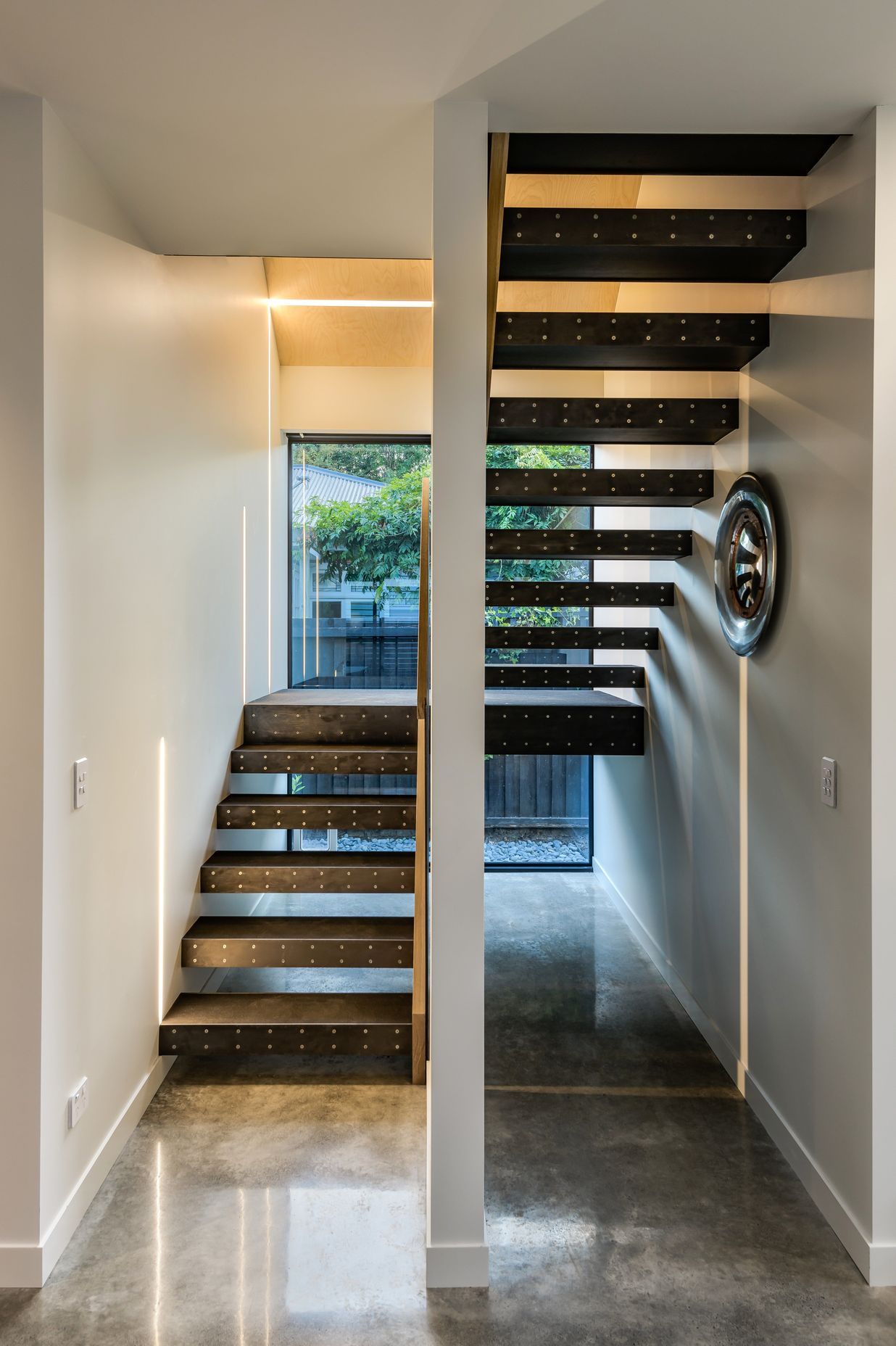 The staircase has an exposed metal stringer, with rubber-clad treads and mild steel fronts.