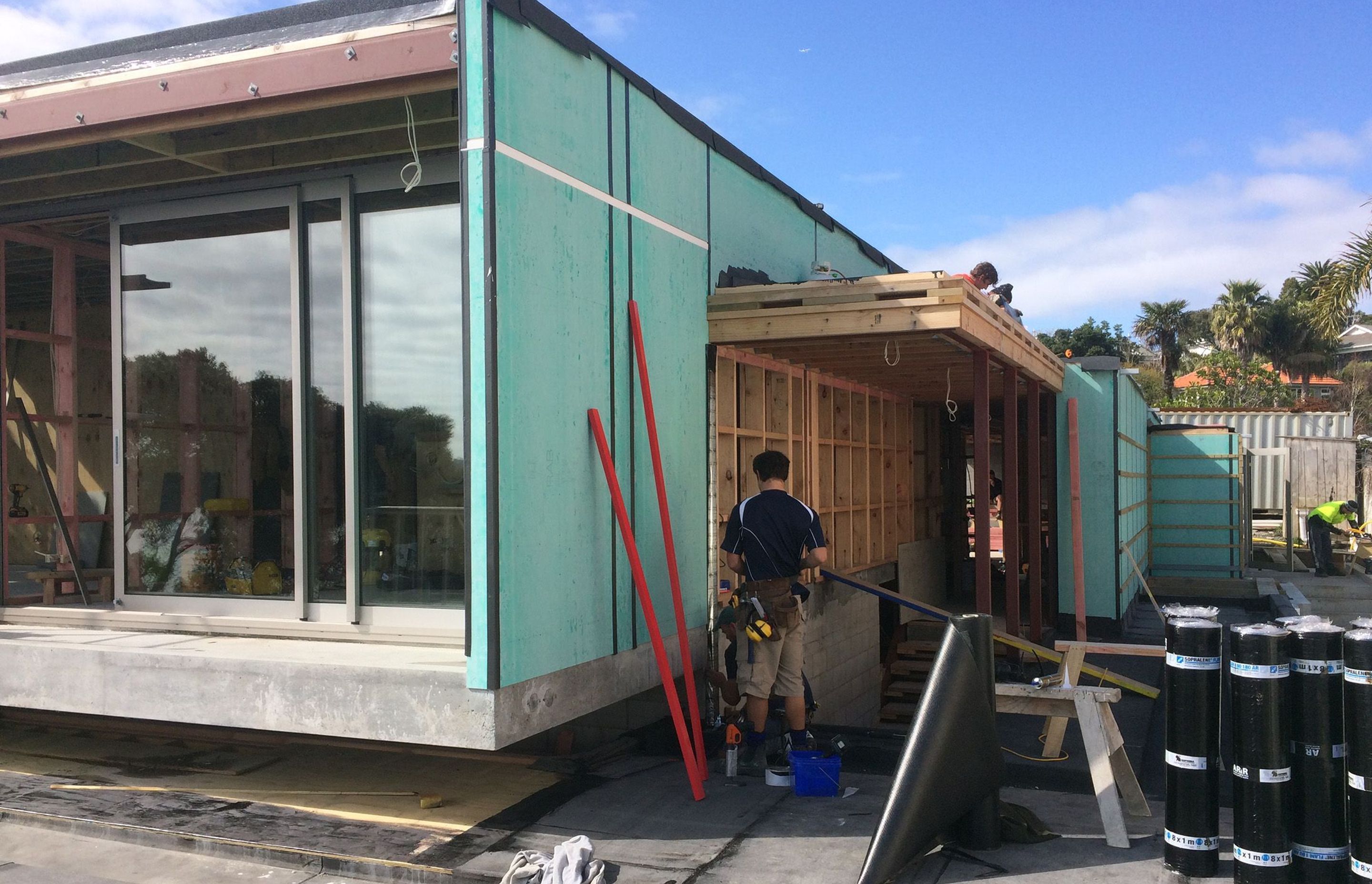 A tradesman installs cladding to the side of the building.