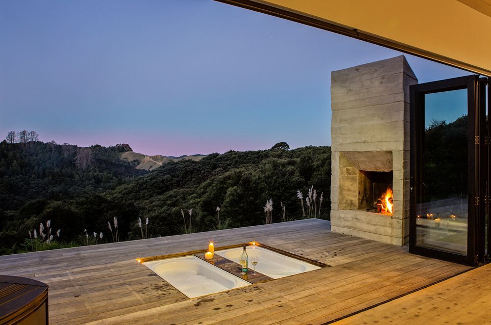 Enjoying bush views and an outdoor fireplace, these twin baths have been inserted into the deck of Back Country House by LTD Architecture and, when not in use, they can also be covered up by a table and chairs. 
