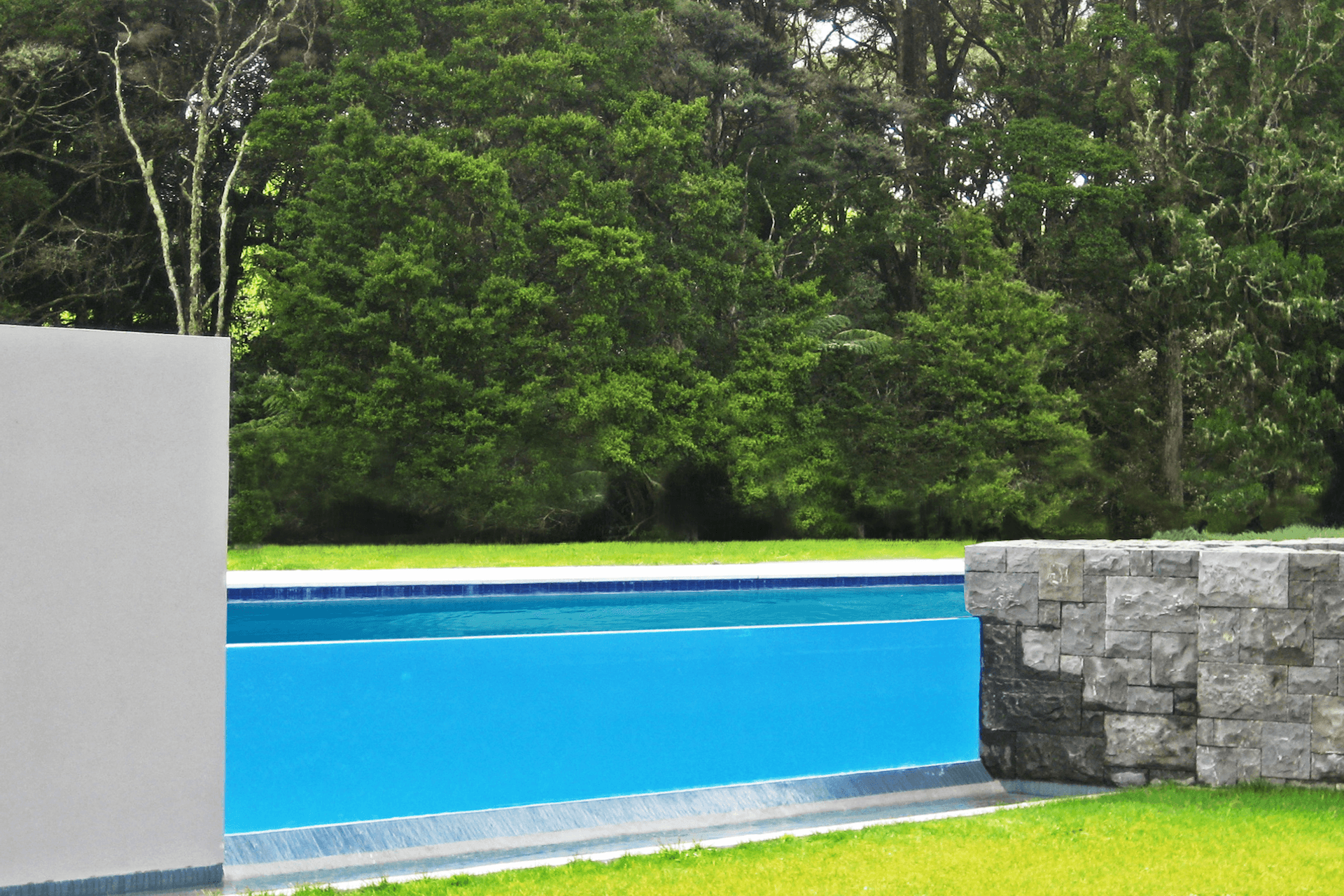 A dramatic glass weir and stone walls  create the pool fencing  and allow this raised level pool to be an absolute feature when viewed from the house