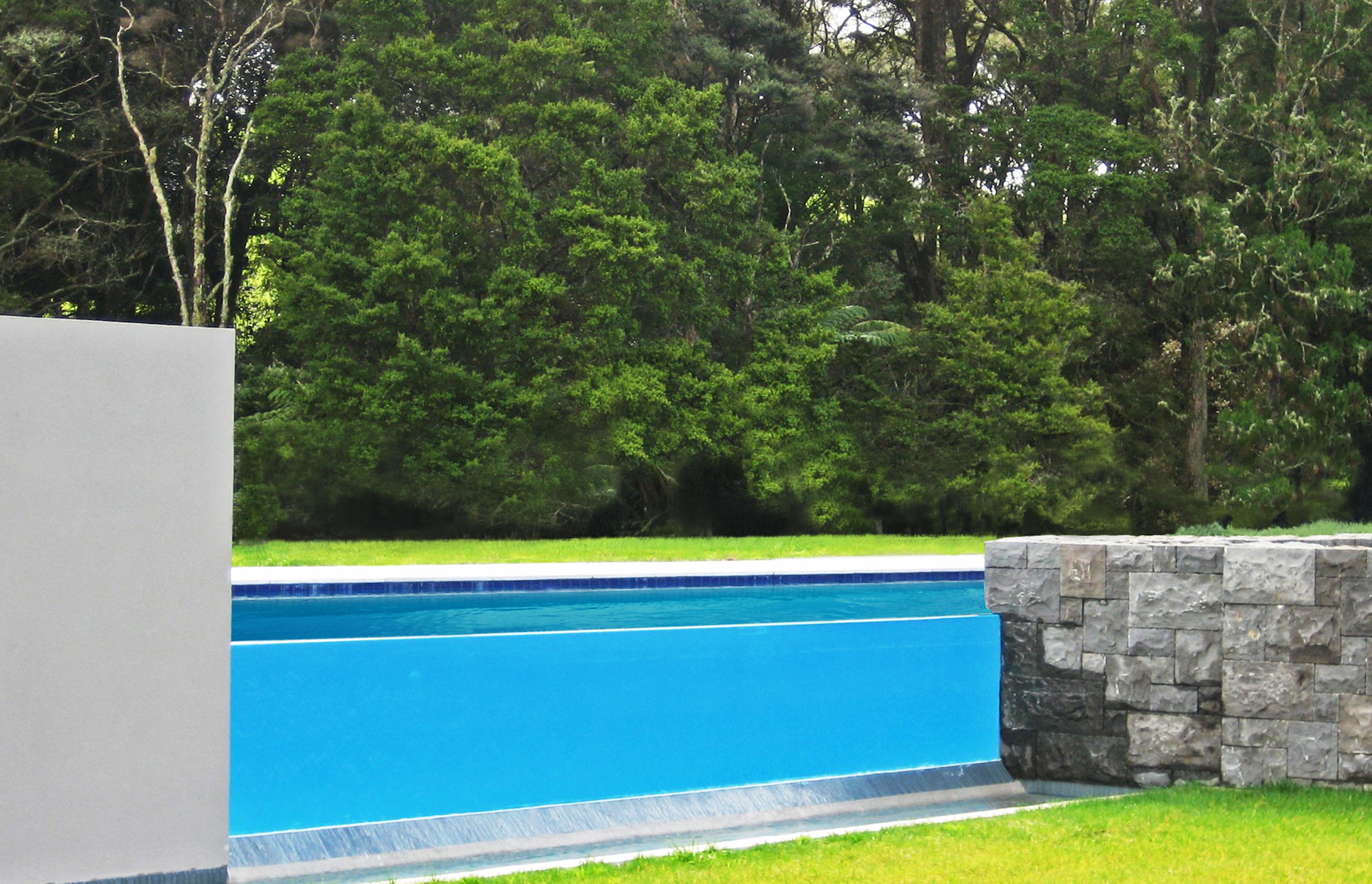 A dramatic glass weir and stone walls  create the pool fencing  and allow this raised level pool to be an absolute feature when viewed from the house