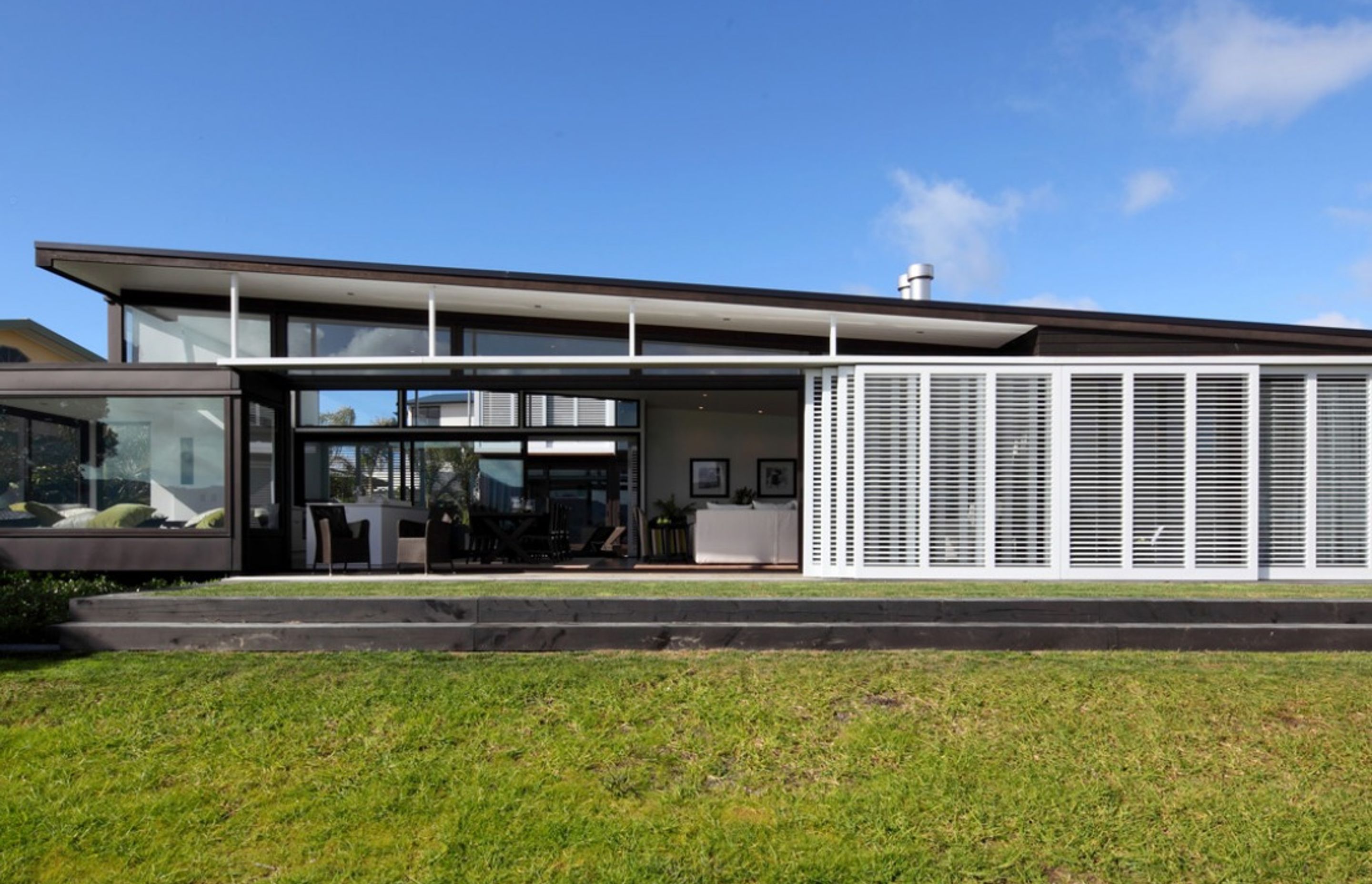 Grandvue Joinery made large sliding timber shutters to provide privacy, light and air filtering in Omaha Beach by Studio 2 Architects.