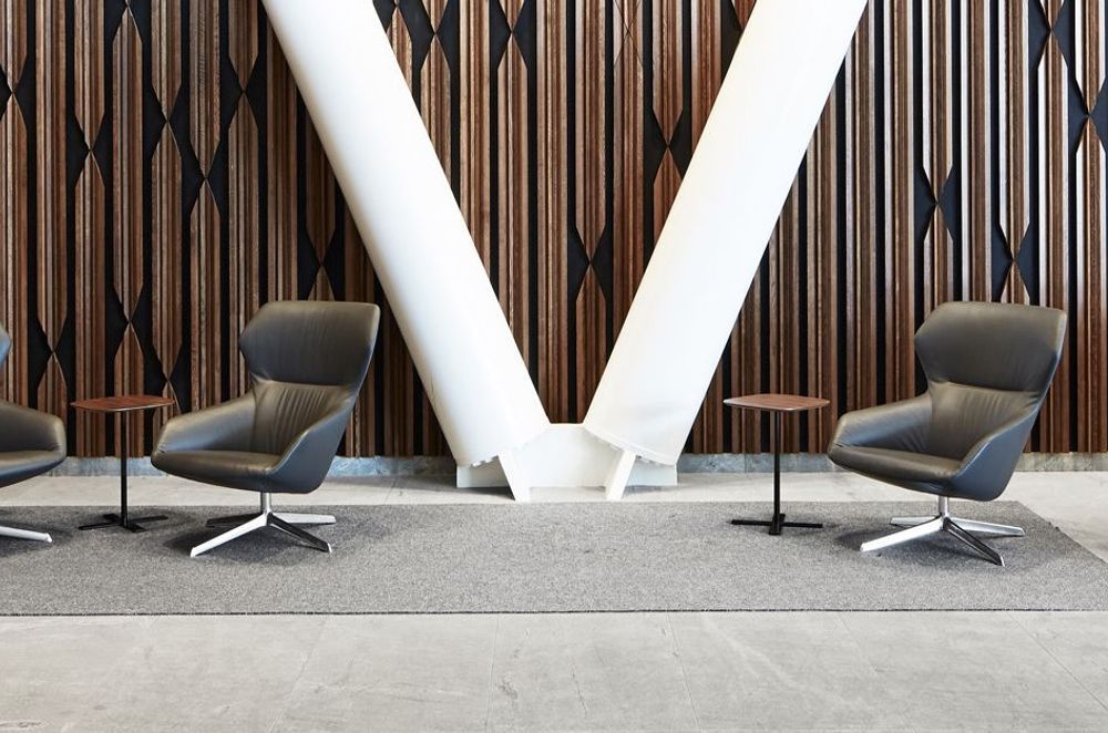 The lobby of XXCQ utilises natural materials, with a timber-panelled feature wall, angular reception desk in polished stone and brass, and curvaceous Scandinavian-style leather-clad chairs.