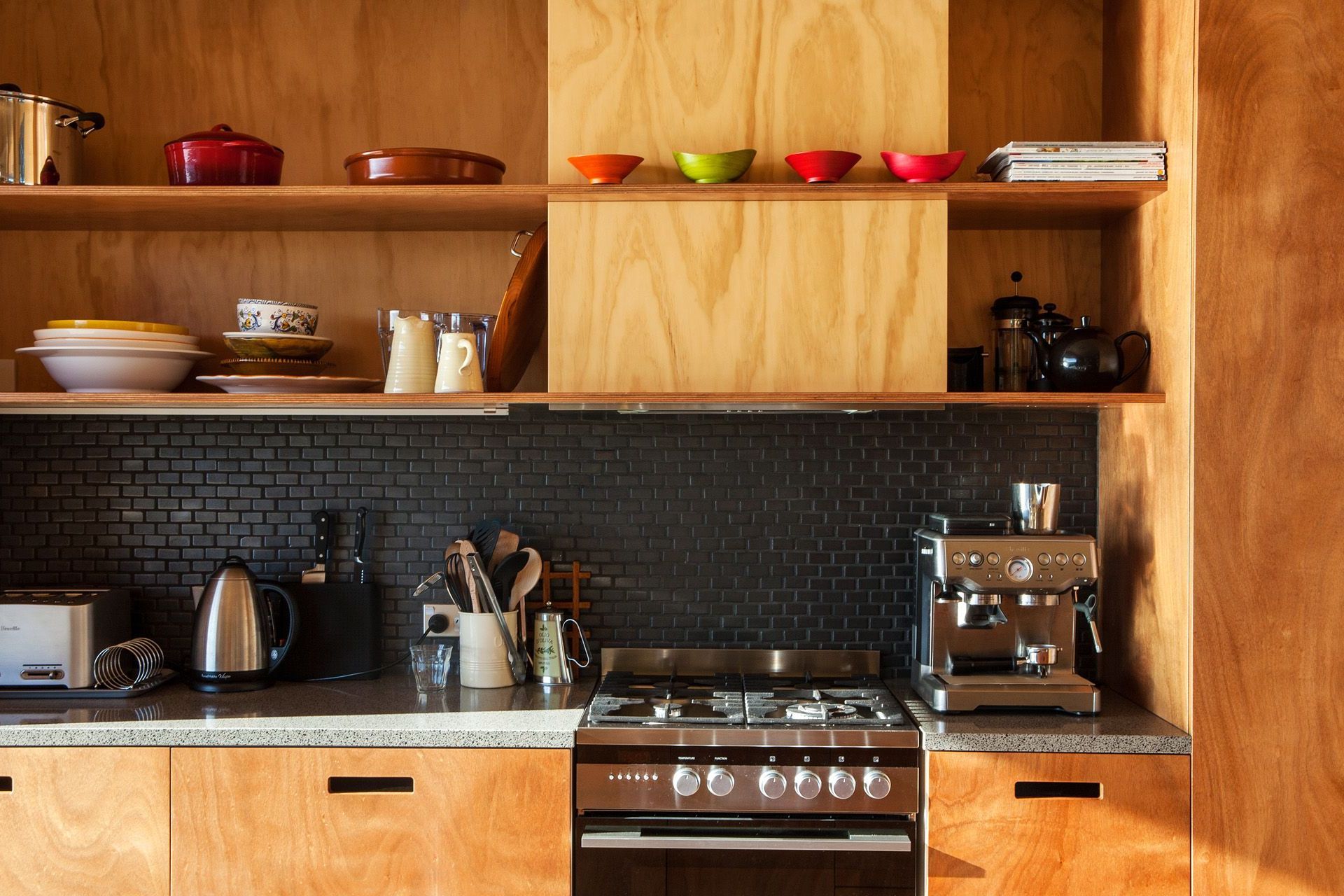 This unique timber-rich kitchen on Great Barrier Island, designed by Green Room Studio, features open shelving.