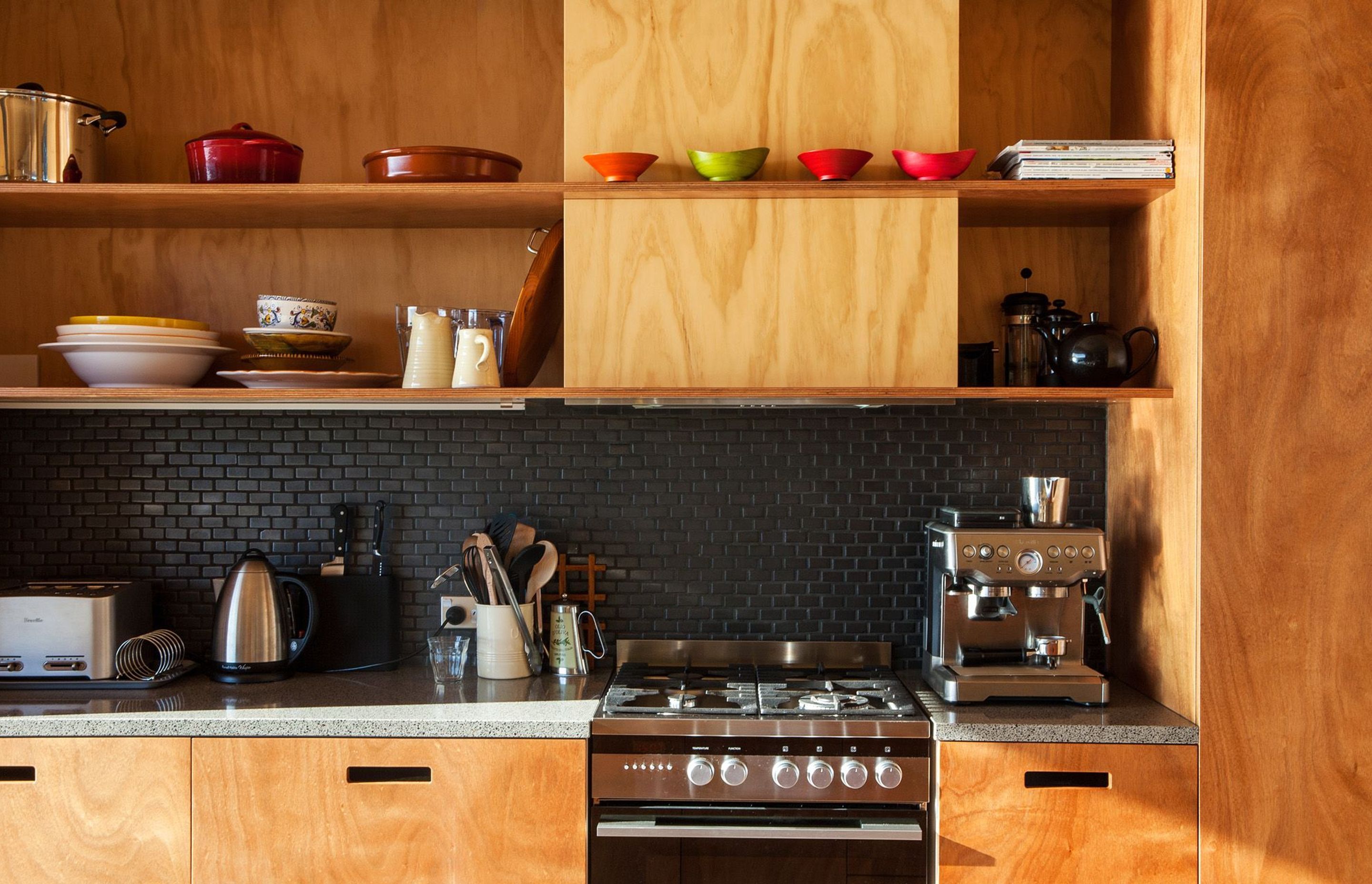 This unique timber-rich kitchen on Great Barrier Island, designed by Green Room Studio, features open shelving.