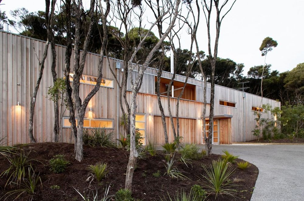 Point House is clad in vertical western red cedar, left to weather to respond to the surrounding Kanuka trees on the site.  By Strachan Group Architects. Photo by Patrick Reynolds.