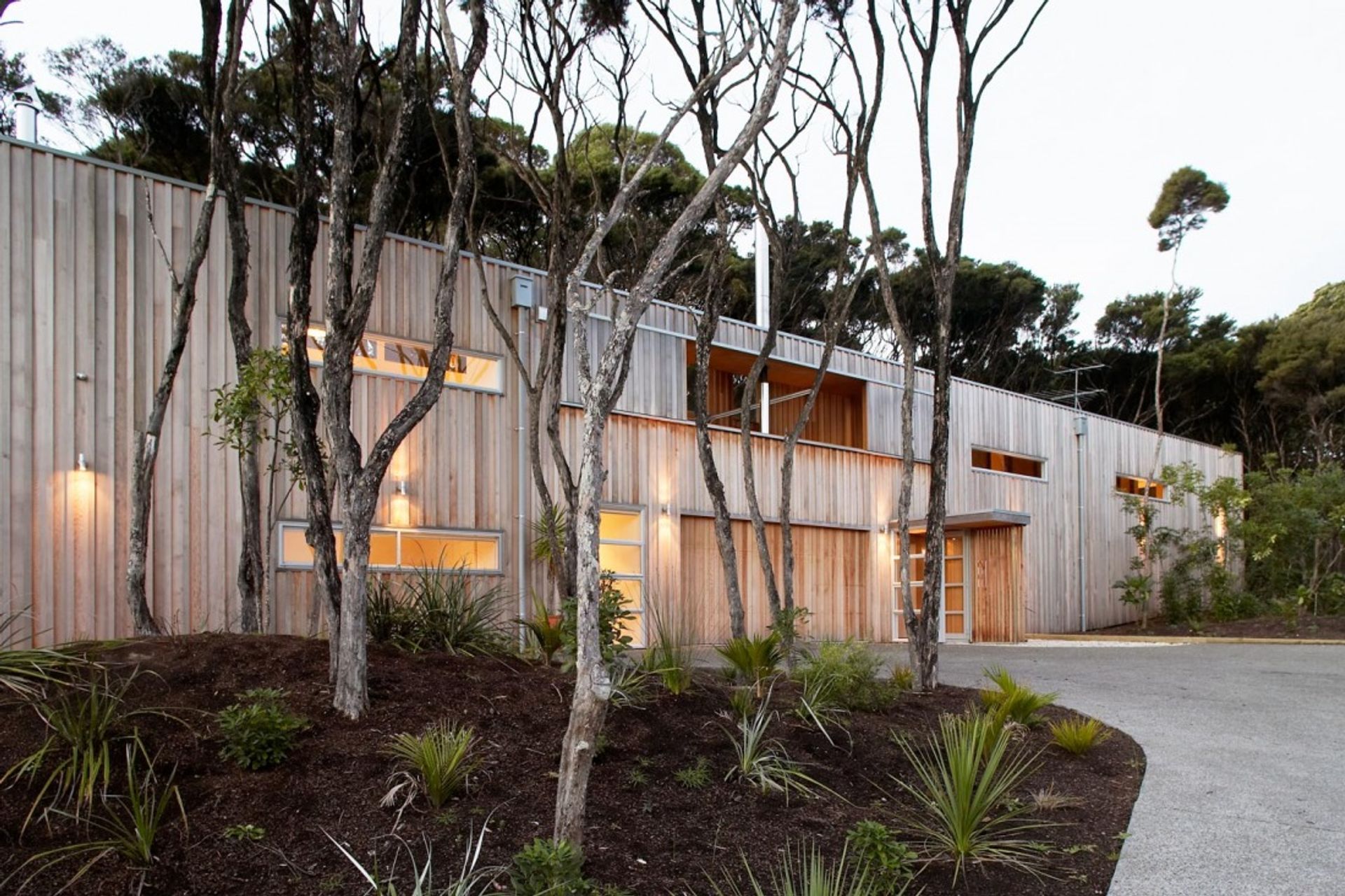Point House is clad in vertical western red cedar, left to weather to respond to the surrounding Kanuka trees on the site.  By Strachan Group Architects. Photo by Patrick Reynolds.