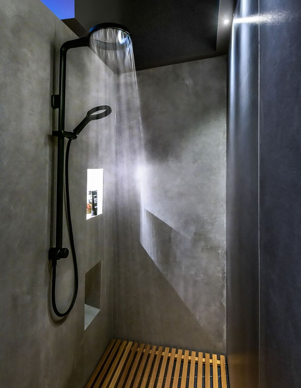 The minimalist shower has a Japanese feel with.a slatted timber floor.