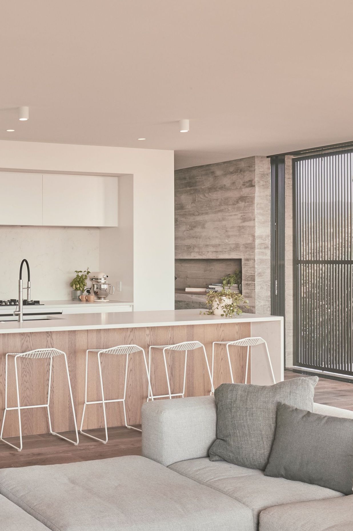 The kitchen is the only area in the house where there is a deviation from a textural, natural palette of materials. Here, it is stripped back to stark white and an oak floor.