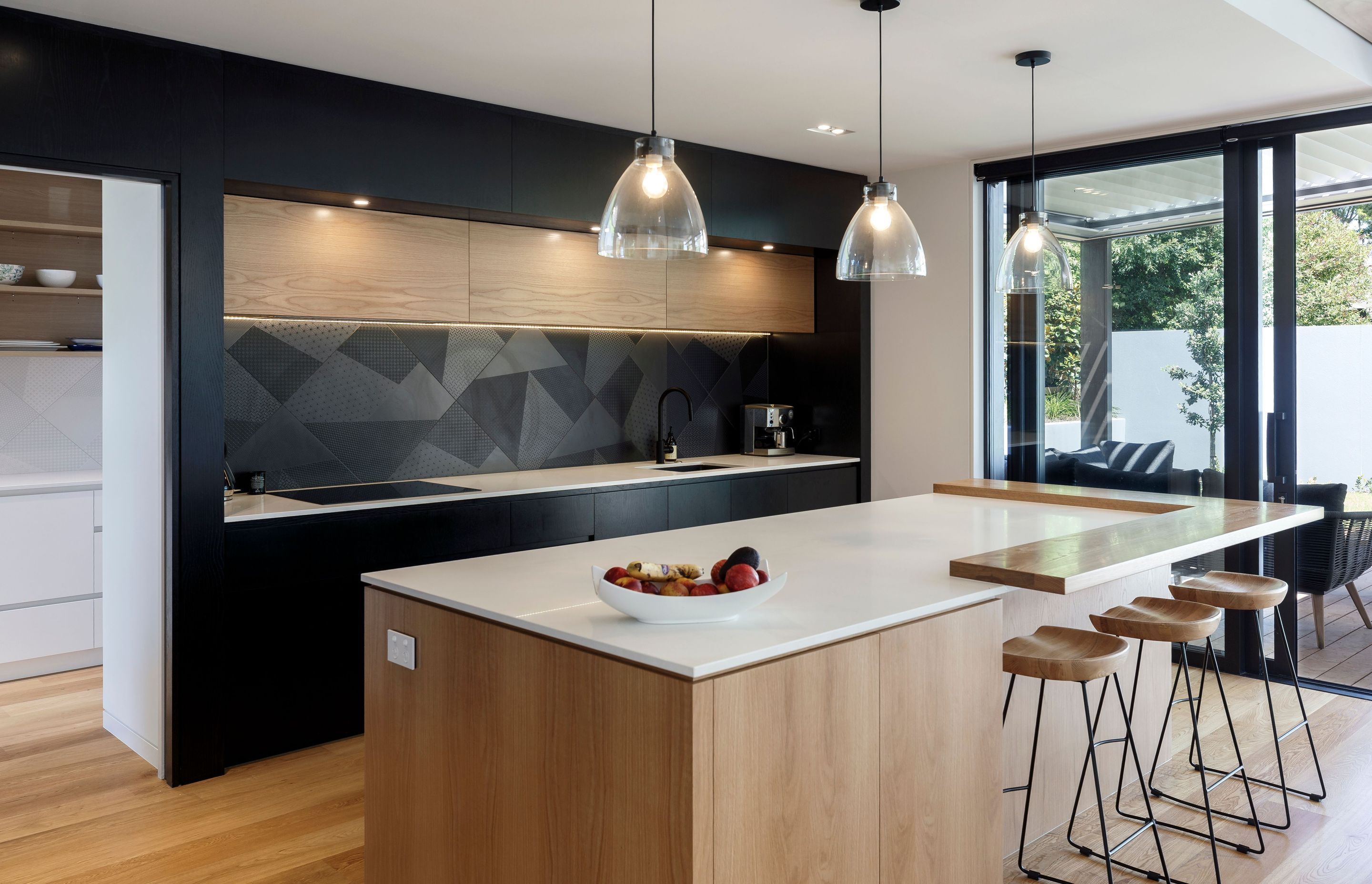 The kitchen and scullery combine natural timber with dramatic monochromatic black and white surfaces.