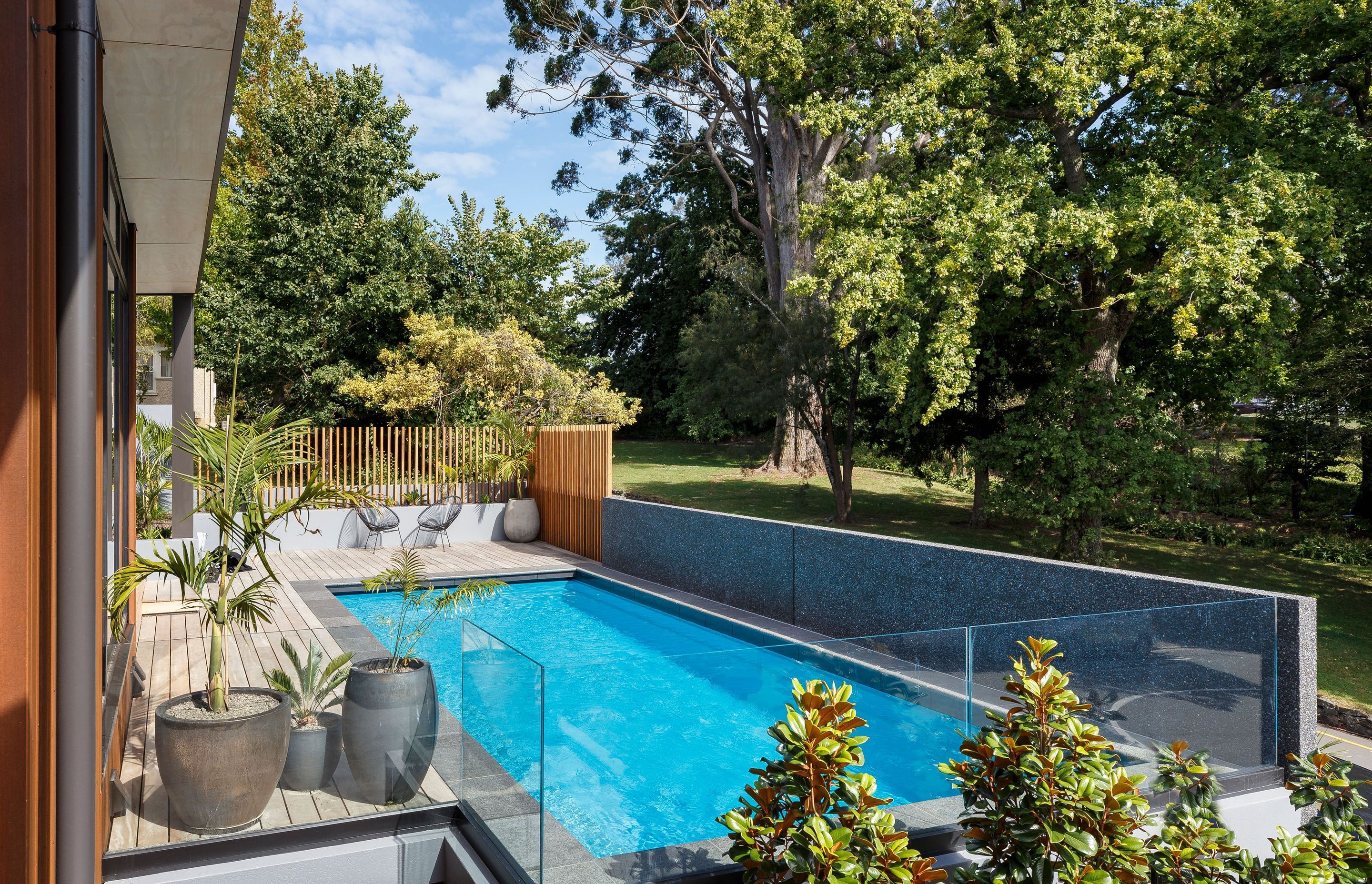 The swimming pool area enjoys shade provided by established trees in the adjacent garden.