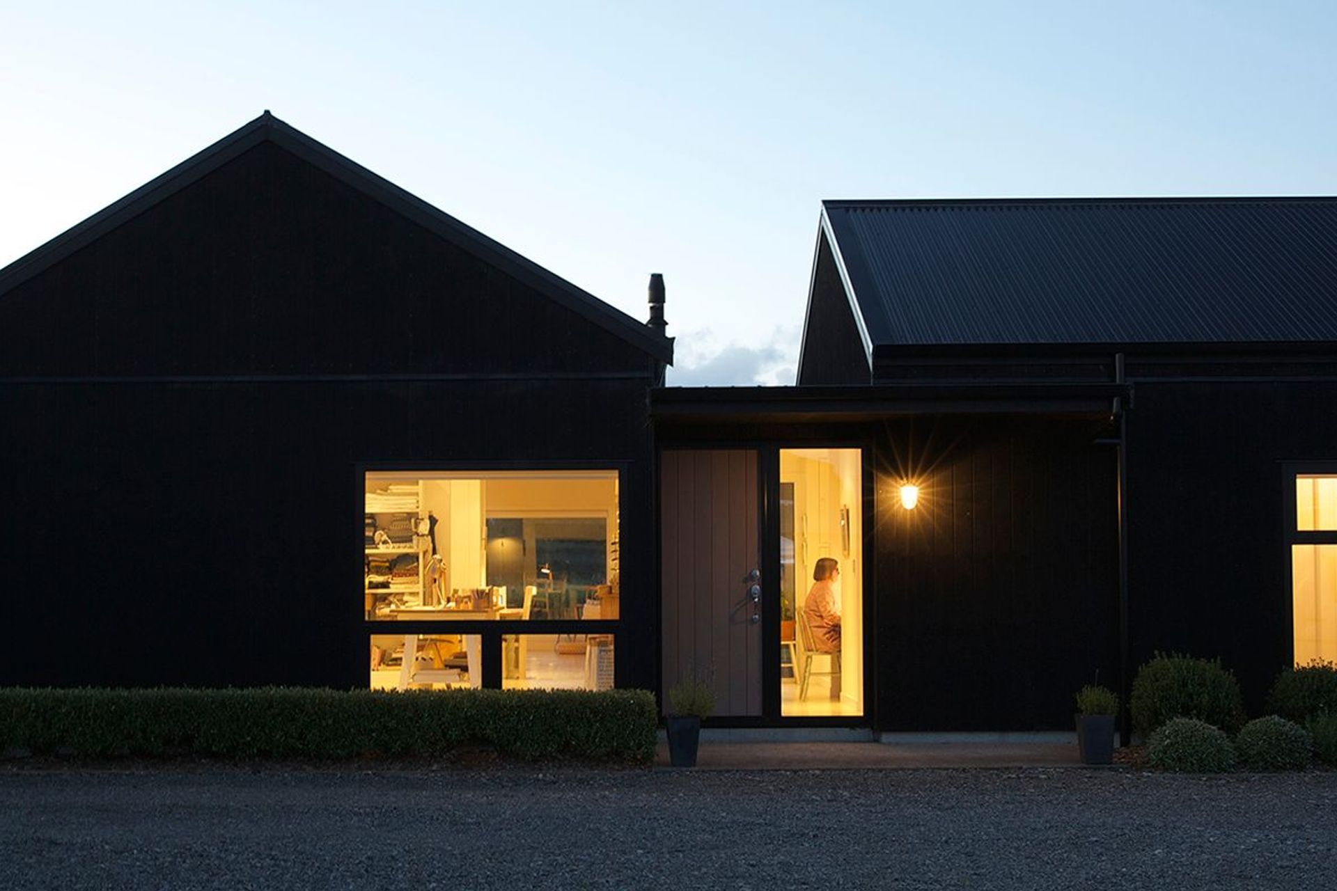 Lit up like a lantern at night, this healthy and sustainable barn house consists of two wings for living and bedrooms with the main entry in between. Photography by Elizabeth Goodall.