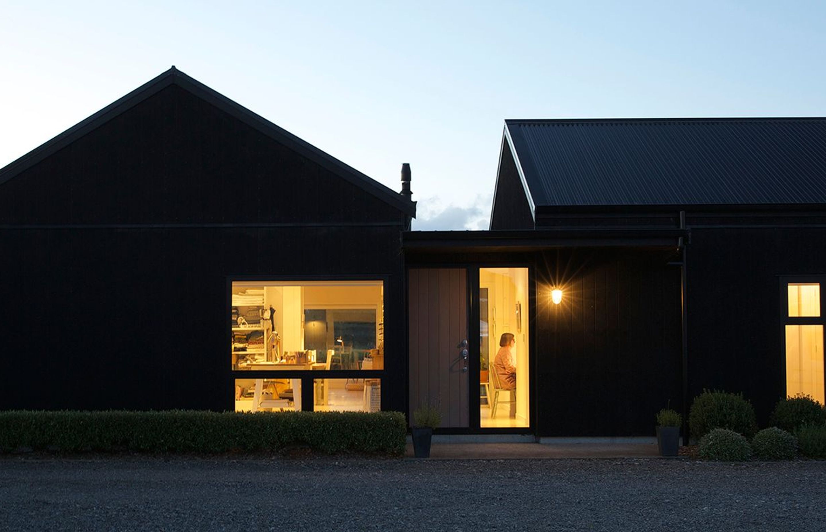 Lit up like a lantern at night, this healthy and sustainable barn house consists of two wings for living and bedrooms with the main entry in between. Photography by Elizabeth Goodall.