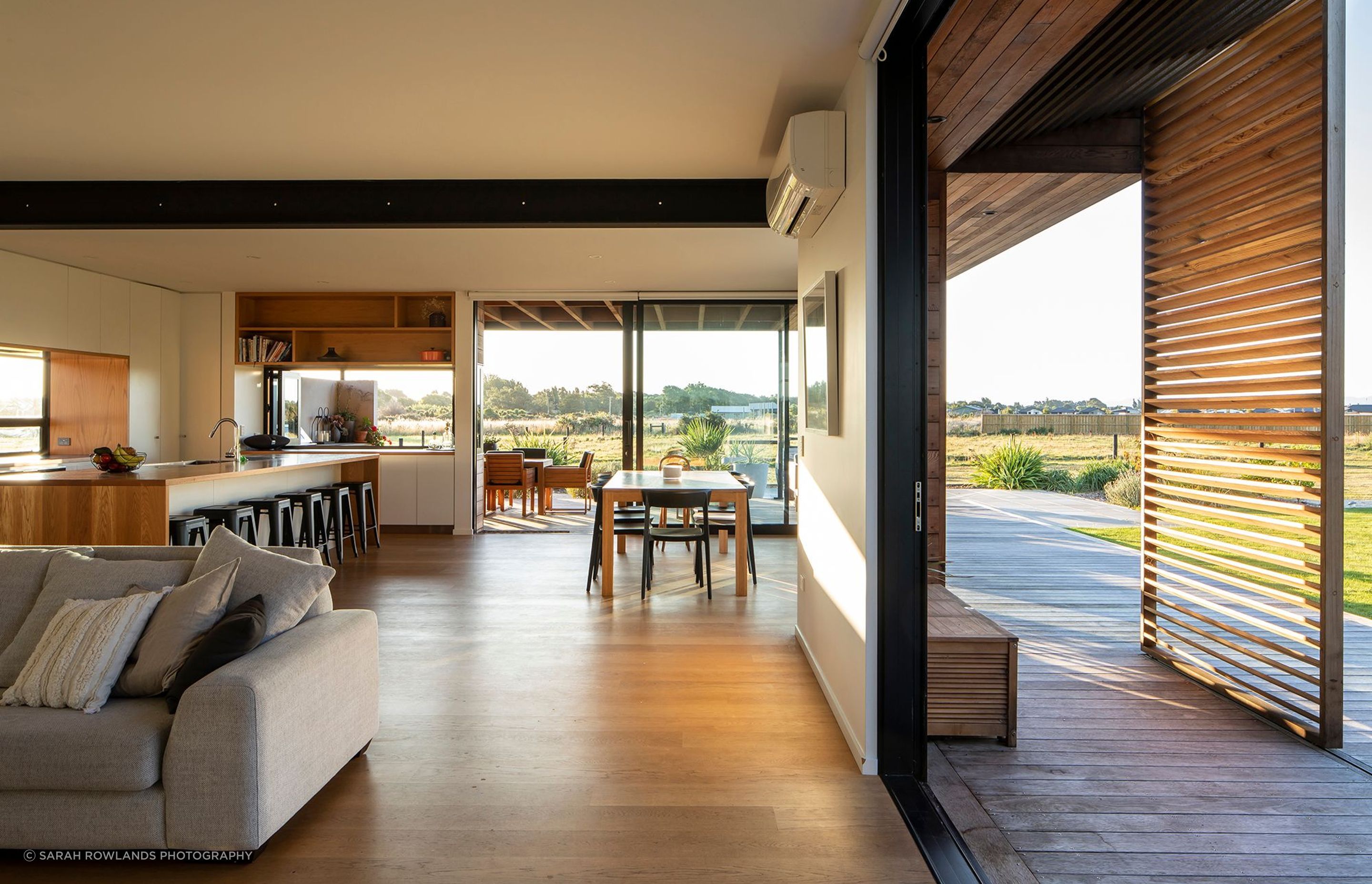 The living area and covered verandah with sliding cedar-slatted screens. For extra functionality when entertaining, the far kitchen bench has windows that open up to the outdoor BBQ area.