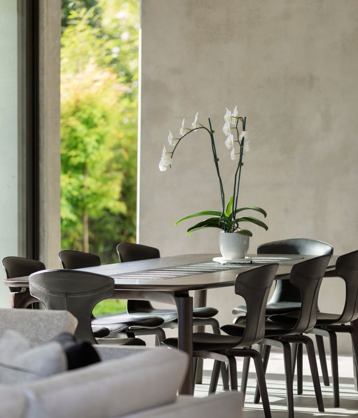 The dining area utilises a harmonious monochromatic materials palette, overlooking the bamboo hedging and small courtyard.