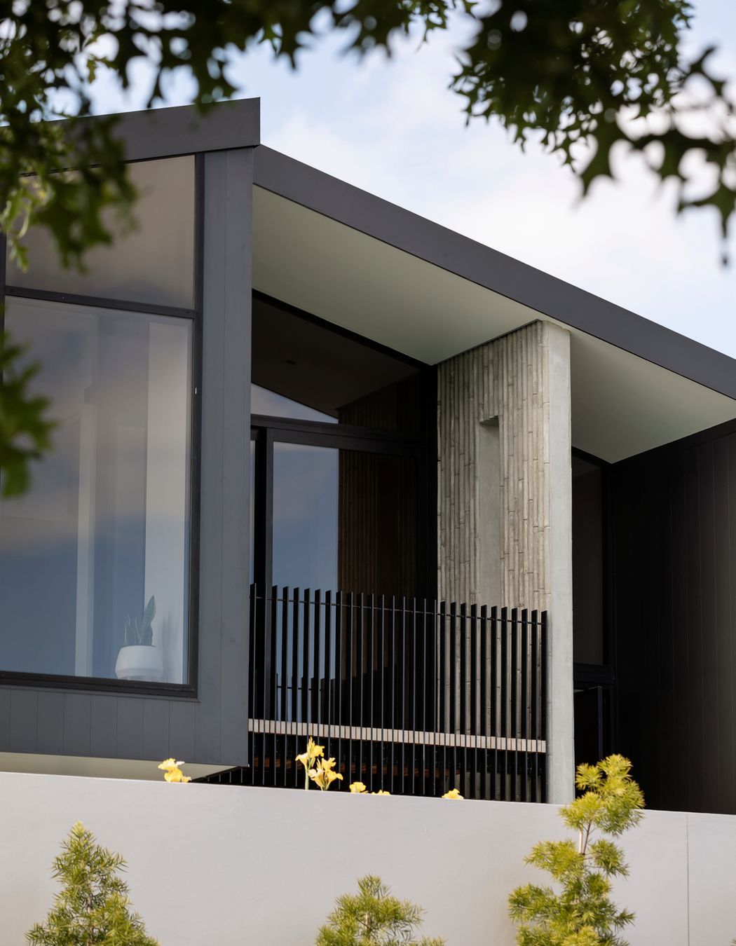 The first-floor balcony is edged with a unique bamboo-patterned concrete wall.