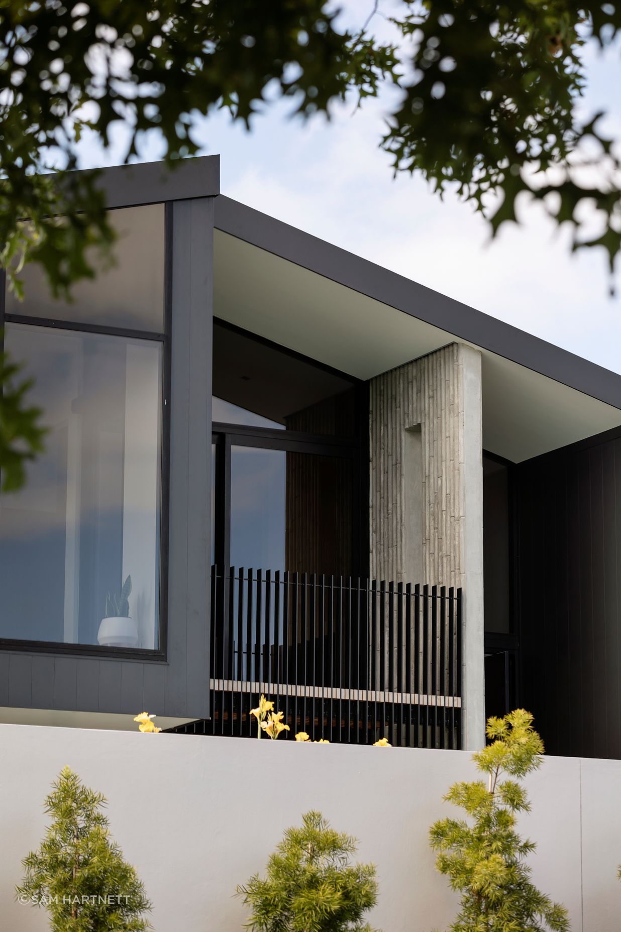 The first-floor balcony is edged with a unique bamboo-patterned concrete wall.