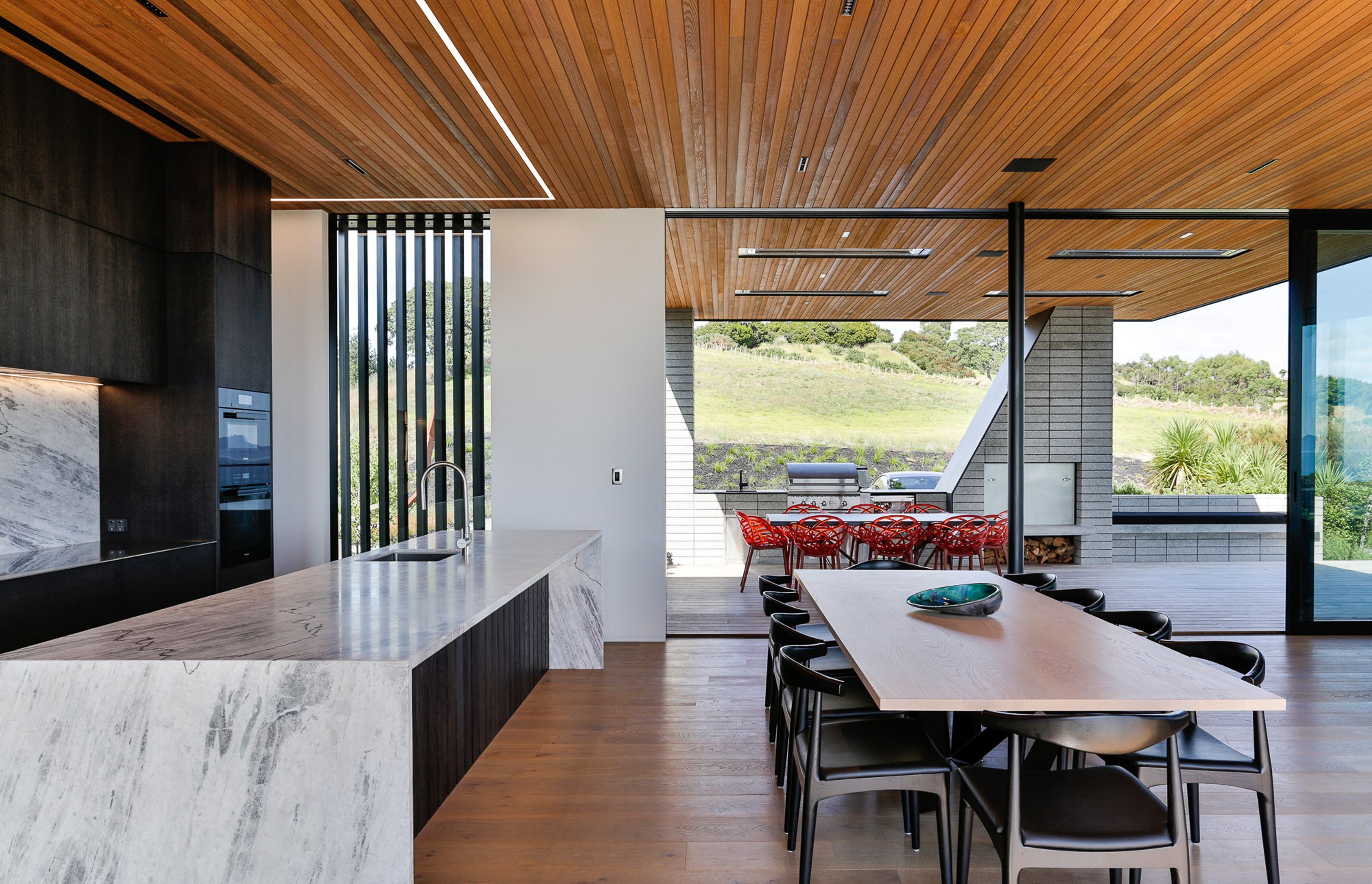 Inside, the material palette reflects the simplicity of the exterior—which is defined by a restrained palette of concrete, cedar and aluminium—with cedar sarking on the ceilings, wide-plank oak flooring and contemporary features such as recessed strip lig