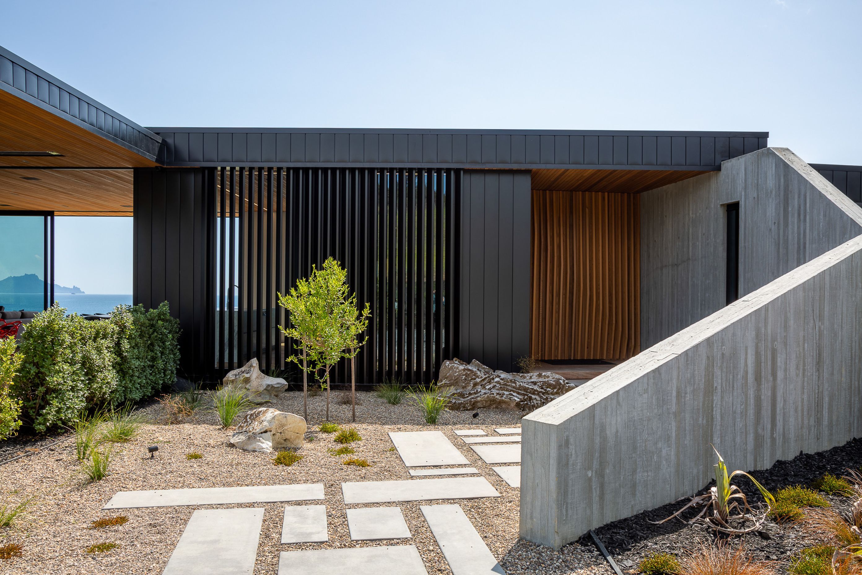The in situ concrete wall and cedar and aluminium fins that define the entry set the angular theme that is seen in the rest of the house, particularly in the striking gabled ends of the two wings.