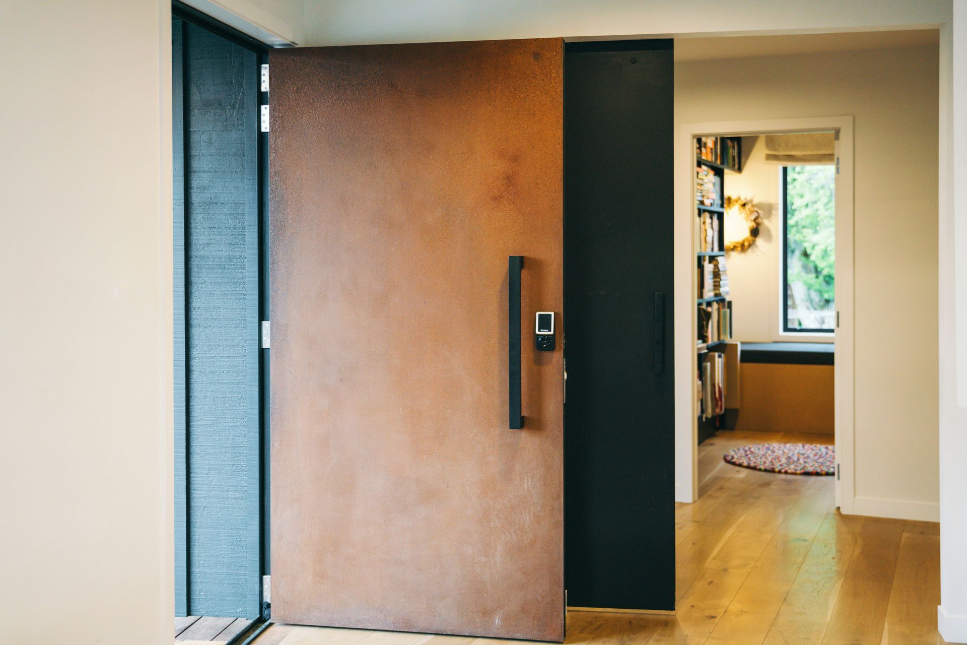 A corten steel door complements the new, contemporary feel of the home and is a bold counterpoint to the black board and batten caldding.