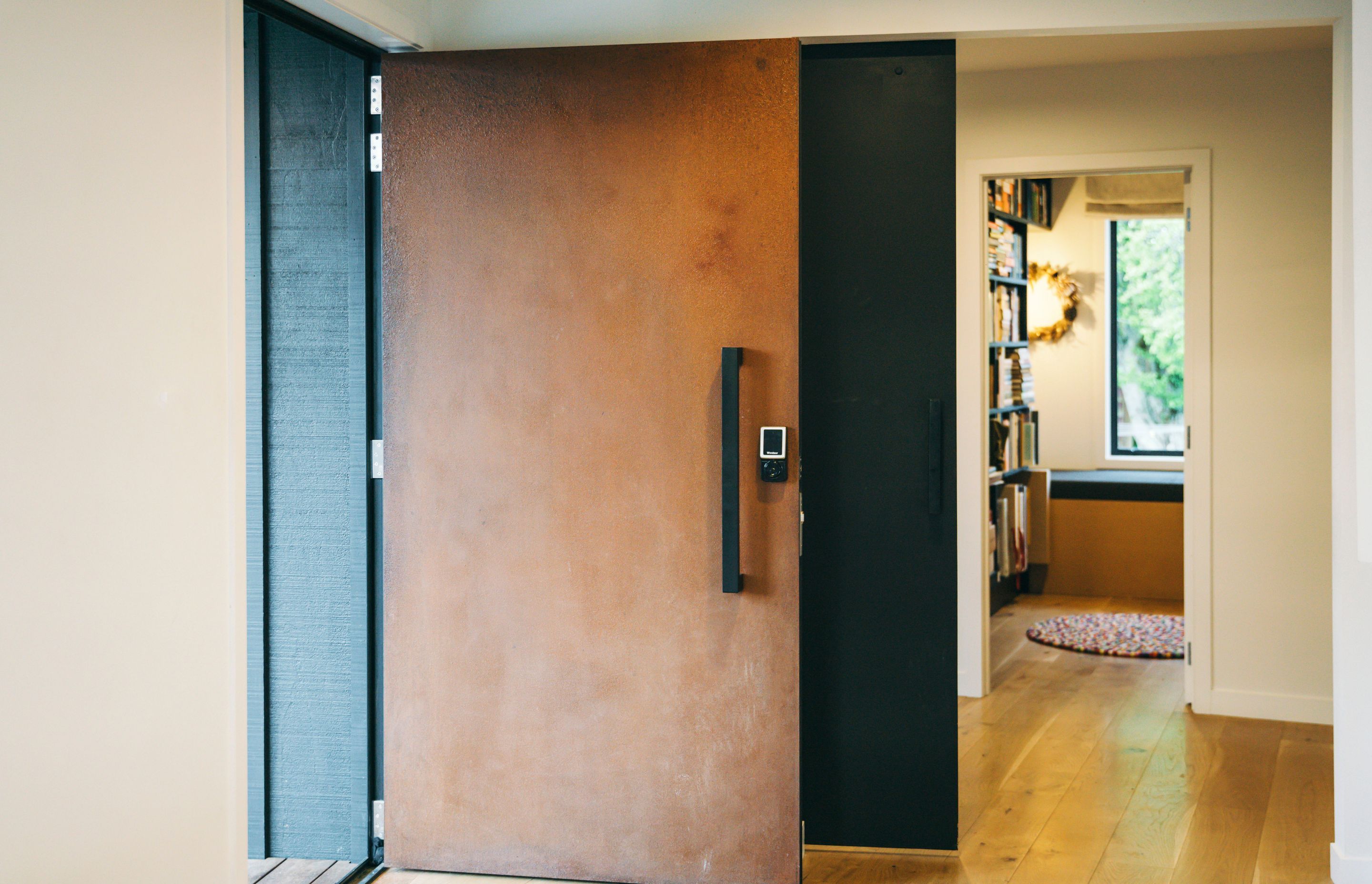 A corten steel door complements the new, contemporary feel of the home and is a bold counterpoint to the black board and batten caldding.
