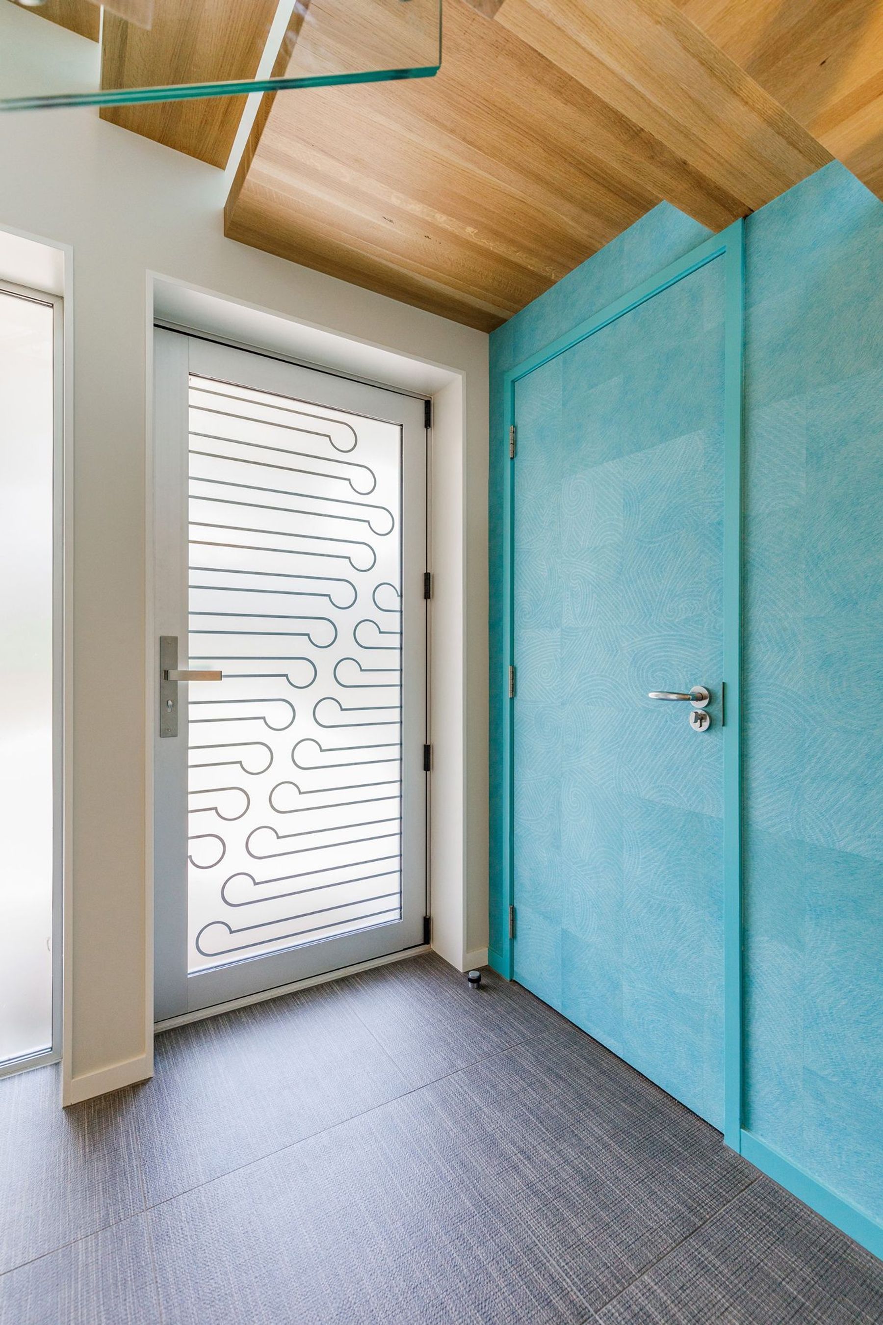 The entrance door really makes an impact. The glass received a customised print using the latest direct-on-glass digital printing technology. The koru pattern is a welcoming symbol of unfolding. The feature wallpaper is Elitis Wallpaper Natives Maori. It runs floor to ceiling over two stories and provides the tone for the upstairs areas.