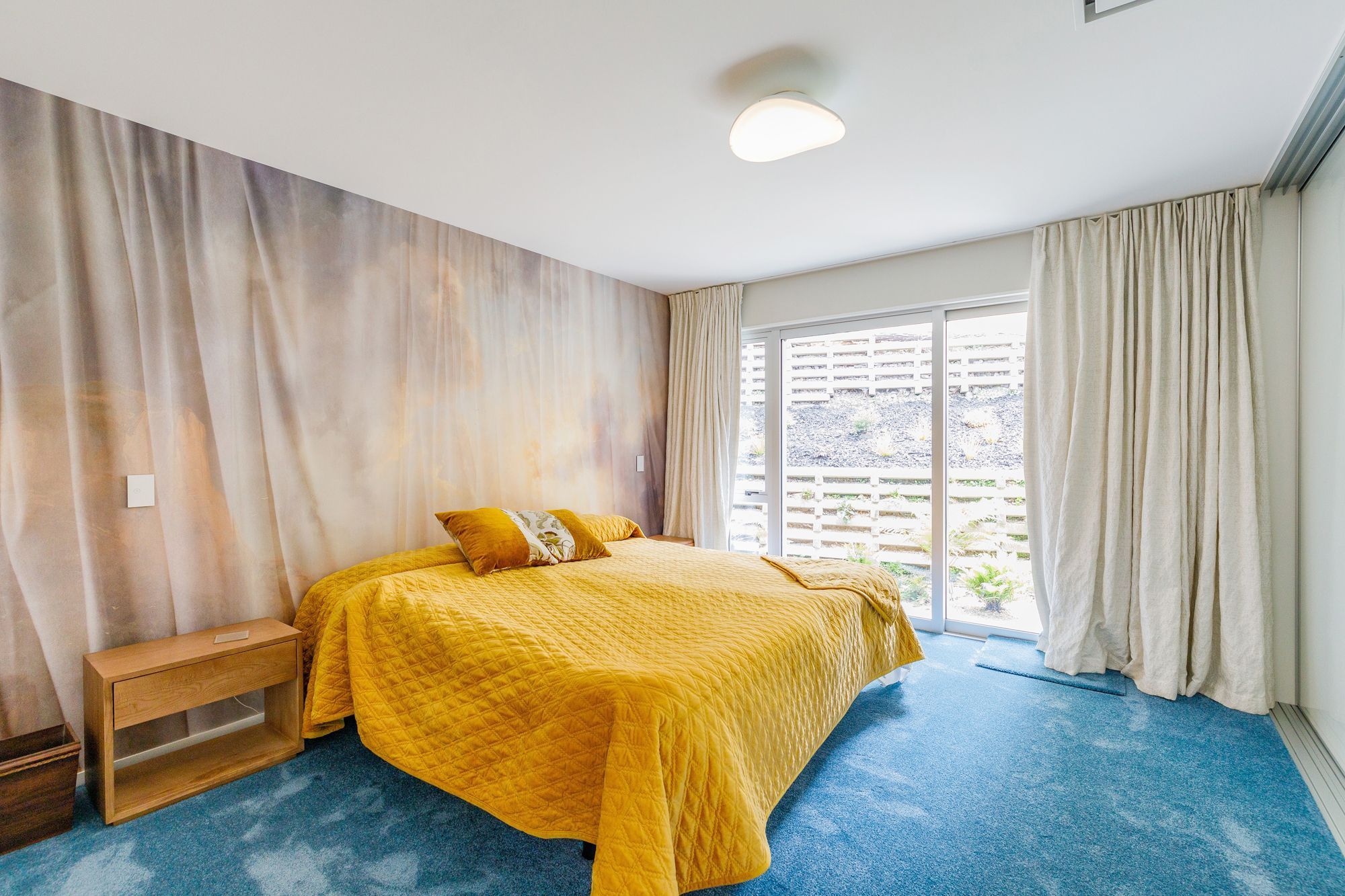 The curtain fabric adds texture, while the colour blends into the wall. The wardrobe sliding doors are back painted glass. The colour is the same as the walls, but the glass adds depth and a different level of gloss.