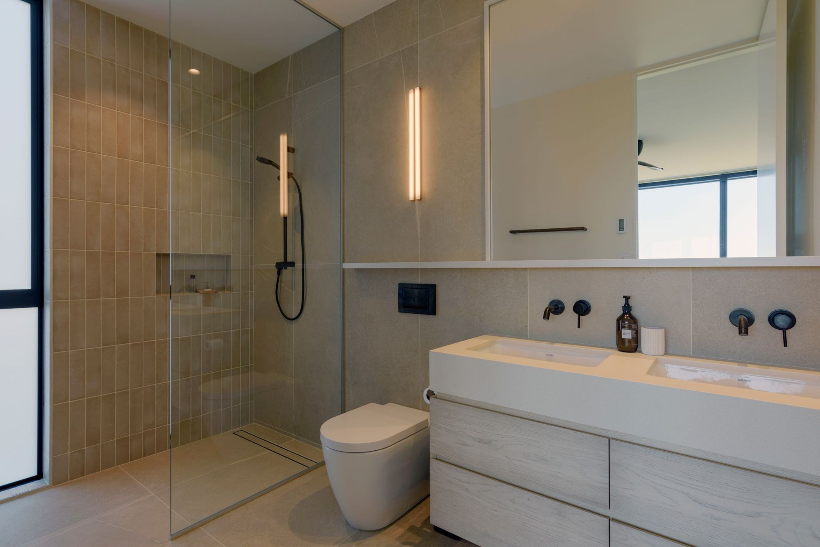 The bathrooms continue the neutral material and colour palette echoing the coastal beiges of the surrounding environment. 