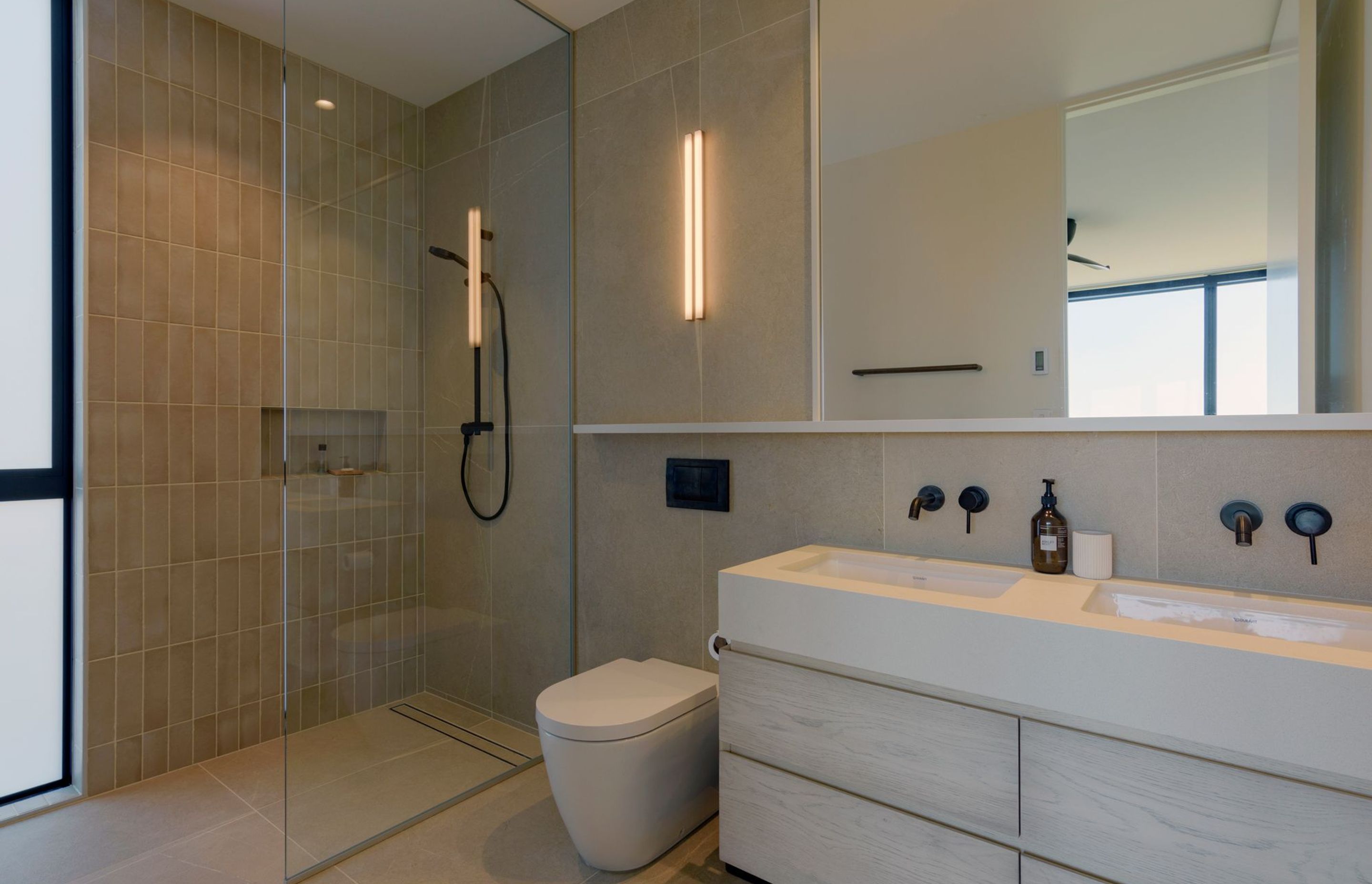 The bathrooms continue the neutral material and colour palette echoing the coastal beiges of the surrounding environment.