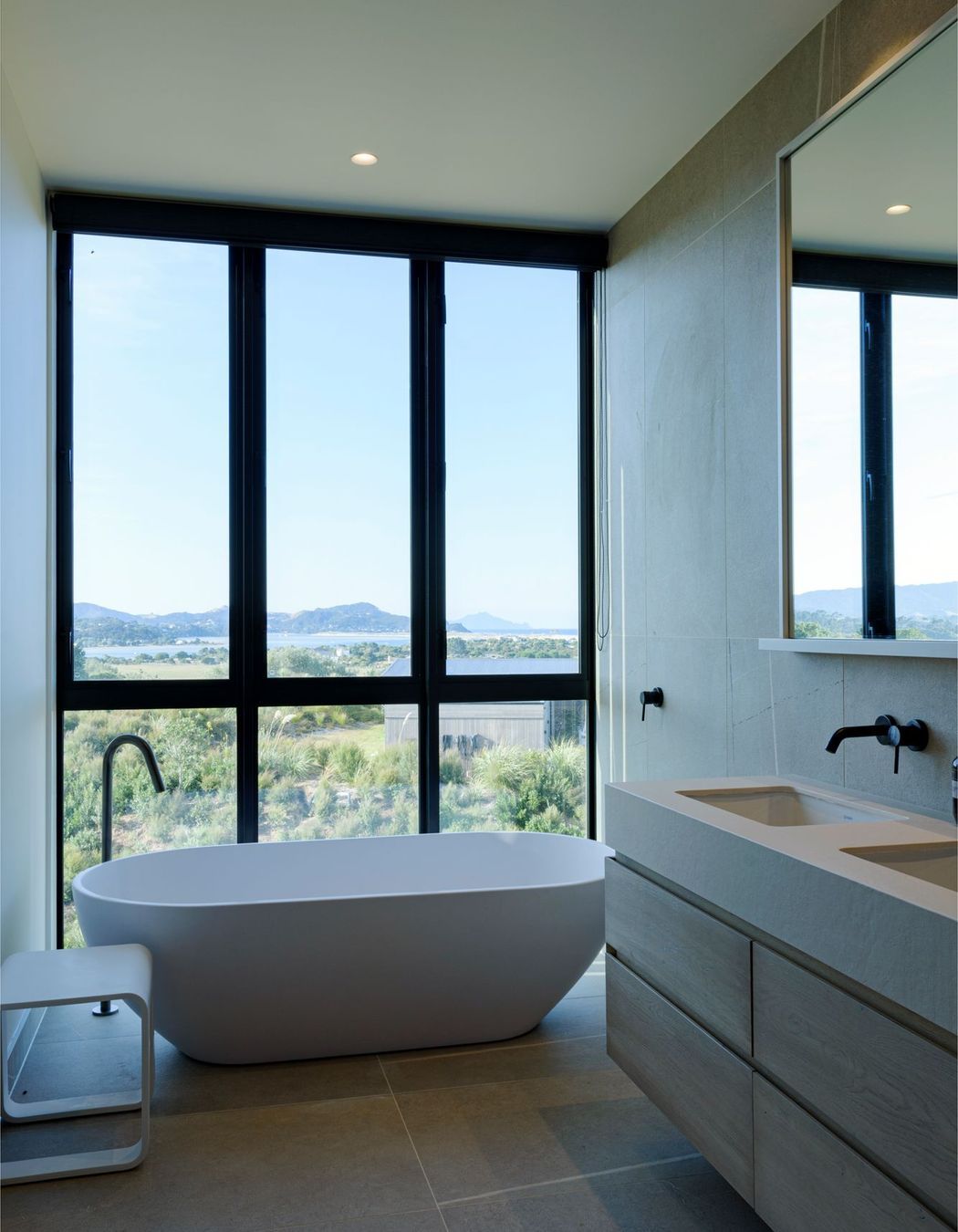 A freestanding bath adjacent to floor-to-ceiling windows makes the most of the expansive views. 