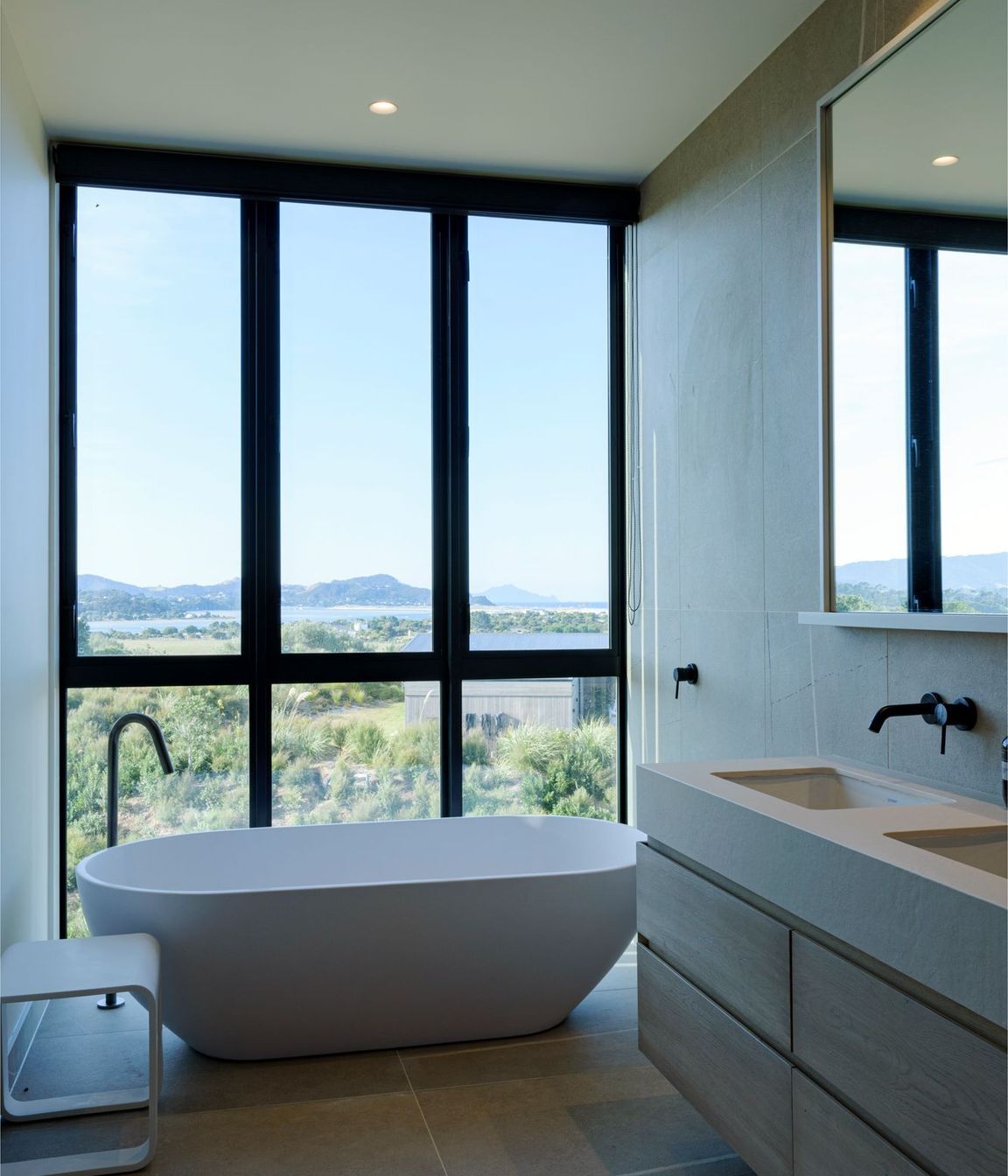 A freestanding bath adjacent to floor-to-ceiling windows makes the most of the expansive views. 