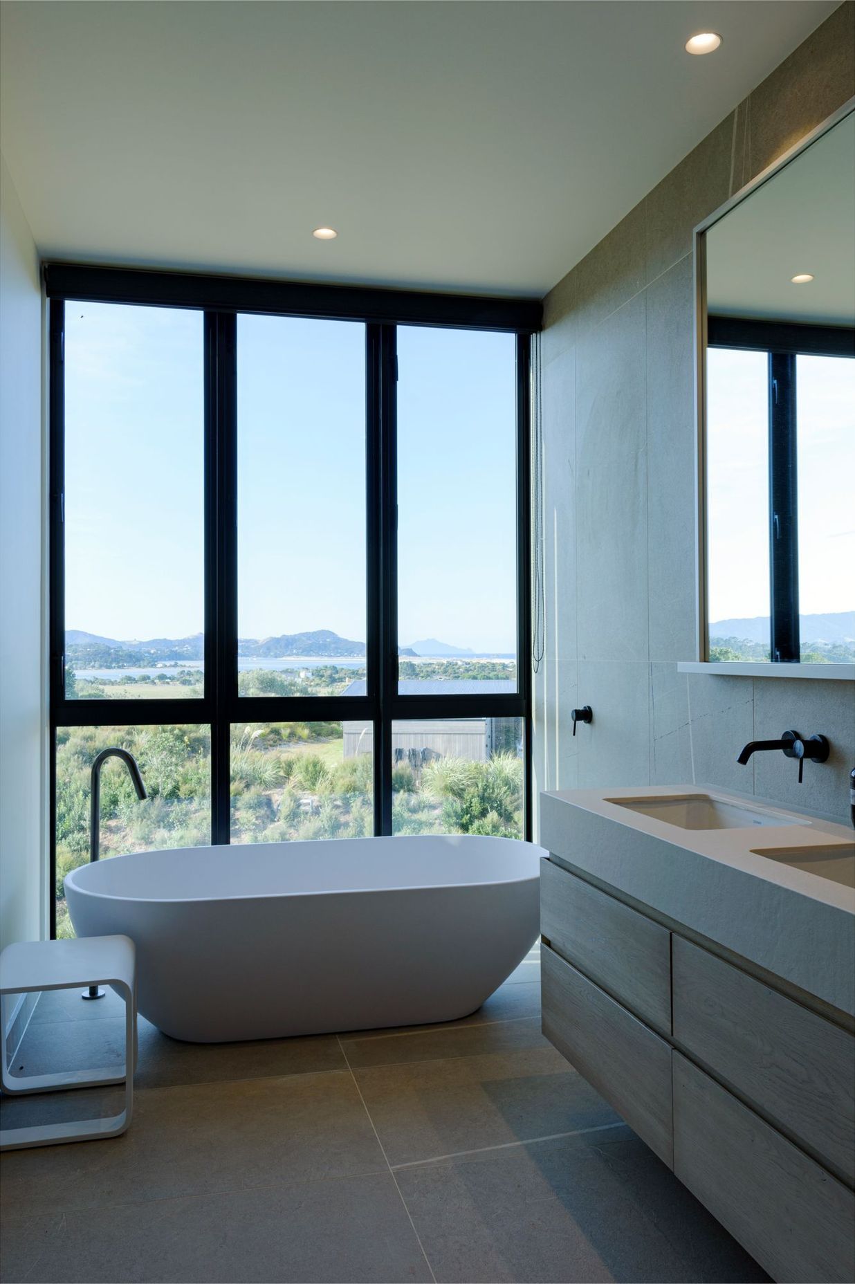 A freestanding bath adjacent to floor-to-ceiling windows makes the most of the expansive views. 