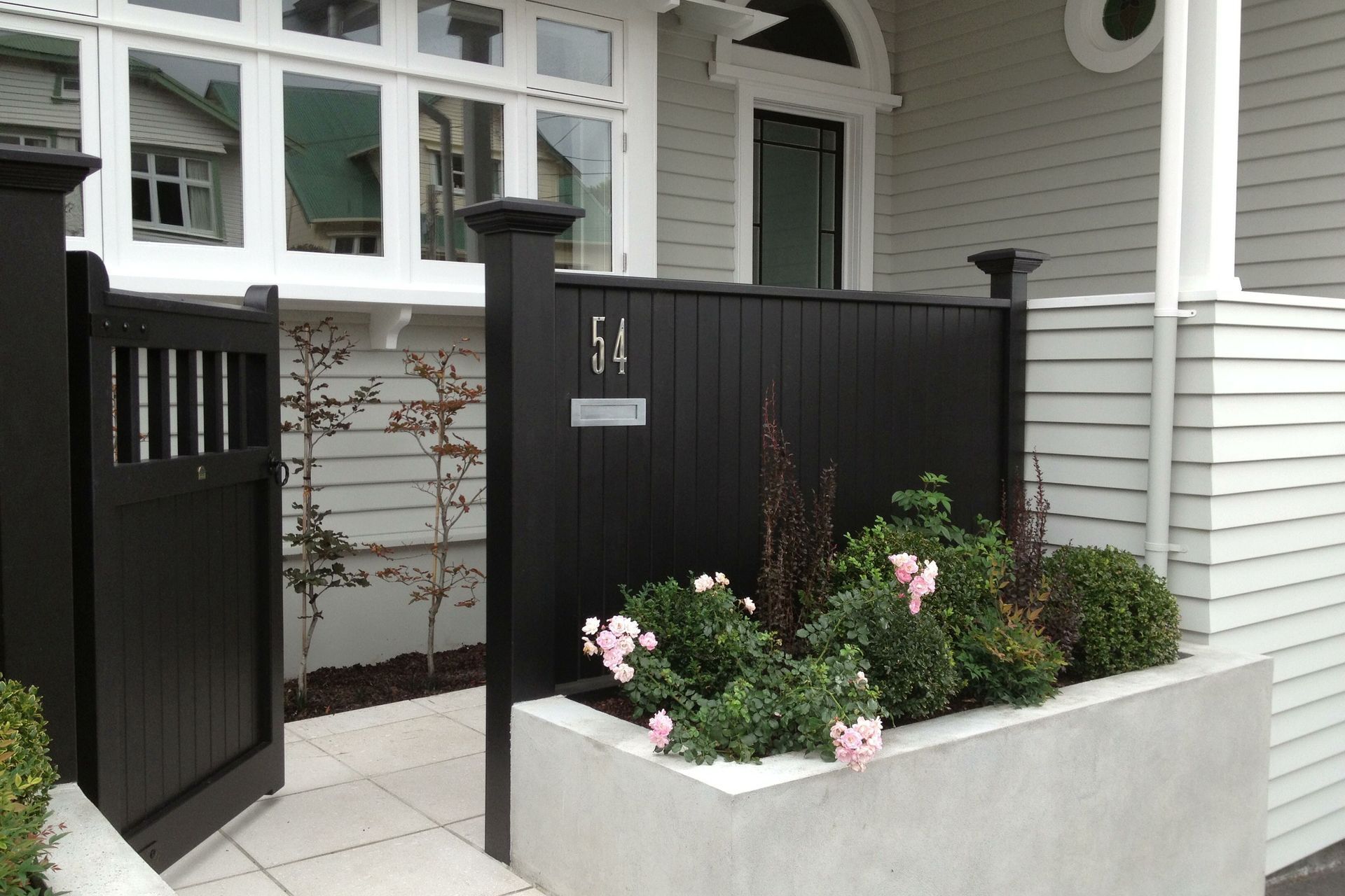 Front entrance &amp; gardens, concrete paving, plaster block wall &amp; black timber fence, Kelburn